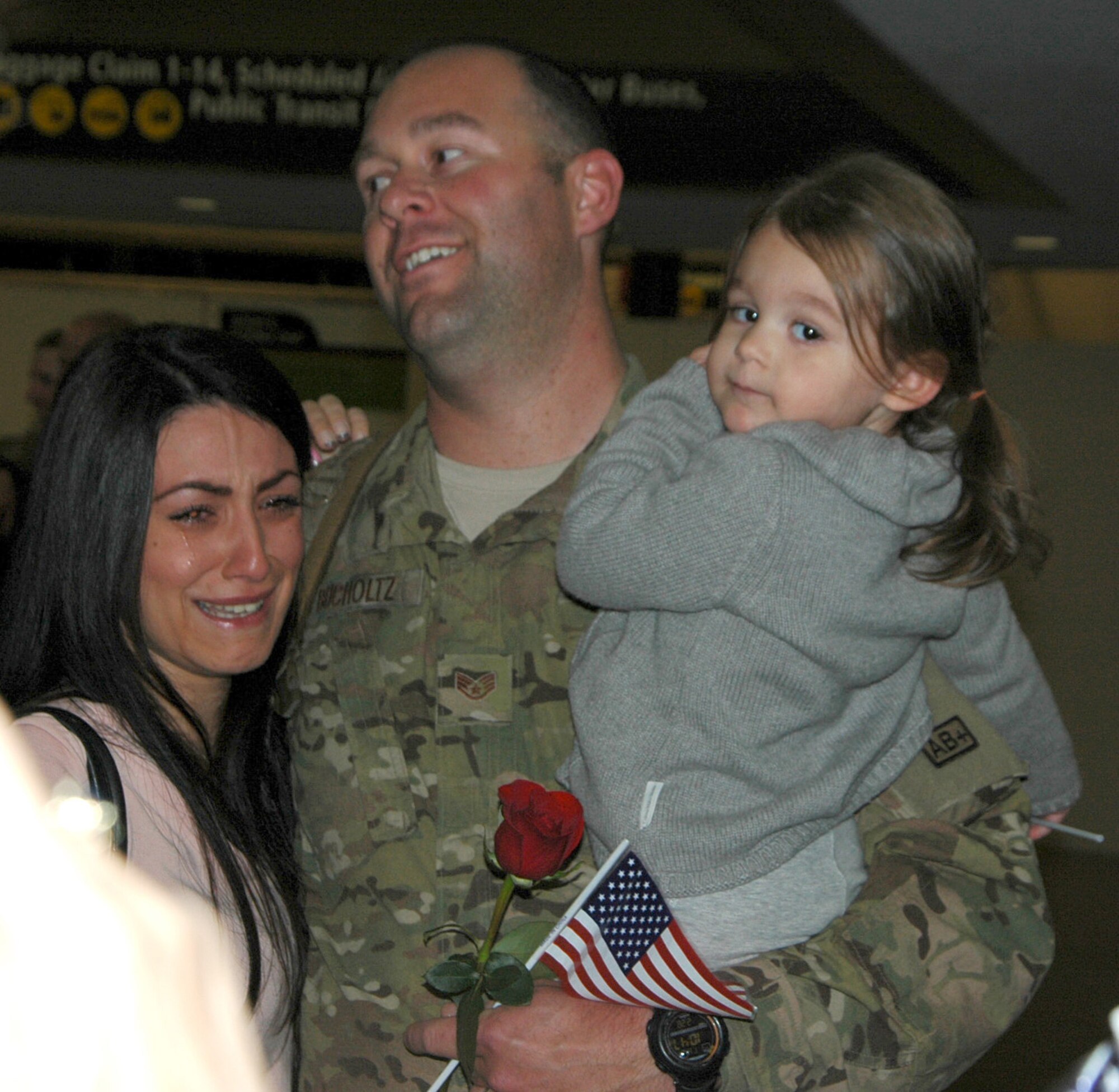 Gokcn Bucholtz, left, tearfully holds on to her husband after his return from a six-month deployment. Staff Sgt. Gary Bucholtz, holding his daugther Olivia, was one of 13 86th Aerial Port Squadron Reservists who returned from Afghanistan Feb. 28. (U.S. Air Force photo by Sandra Pishner)