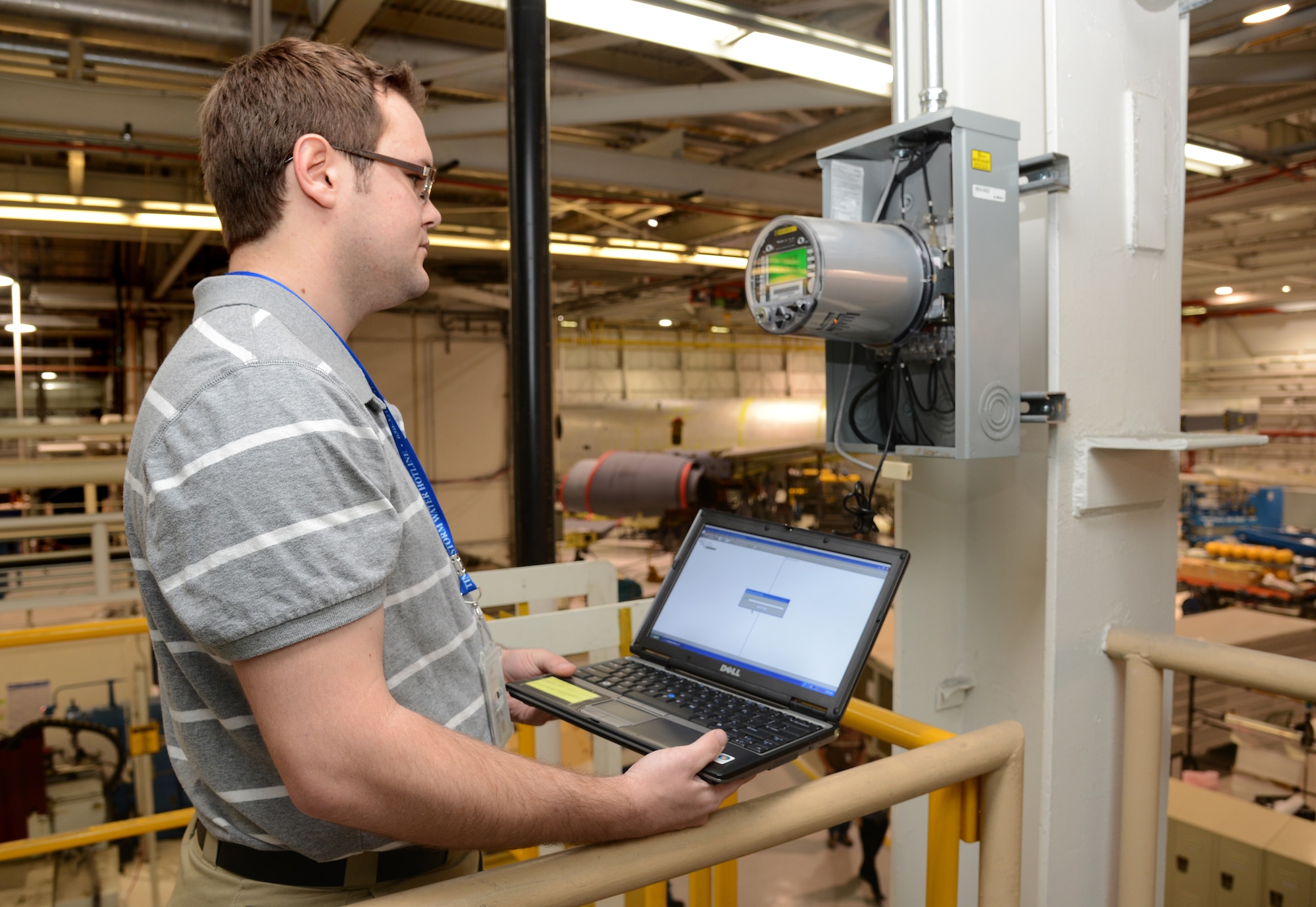 Zach Bright, a civil engineer with the 72nd Air Base Wing Civil Engineering Directorate Programs Division, downloads consumption data from a meter in Bldg. 3001. This data is used by engineers to track electrical usage and is used as a baseline for energy savings and energy reduction modifications to industrial electrical loads. (Air Force photo by Kelly White)