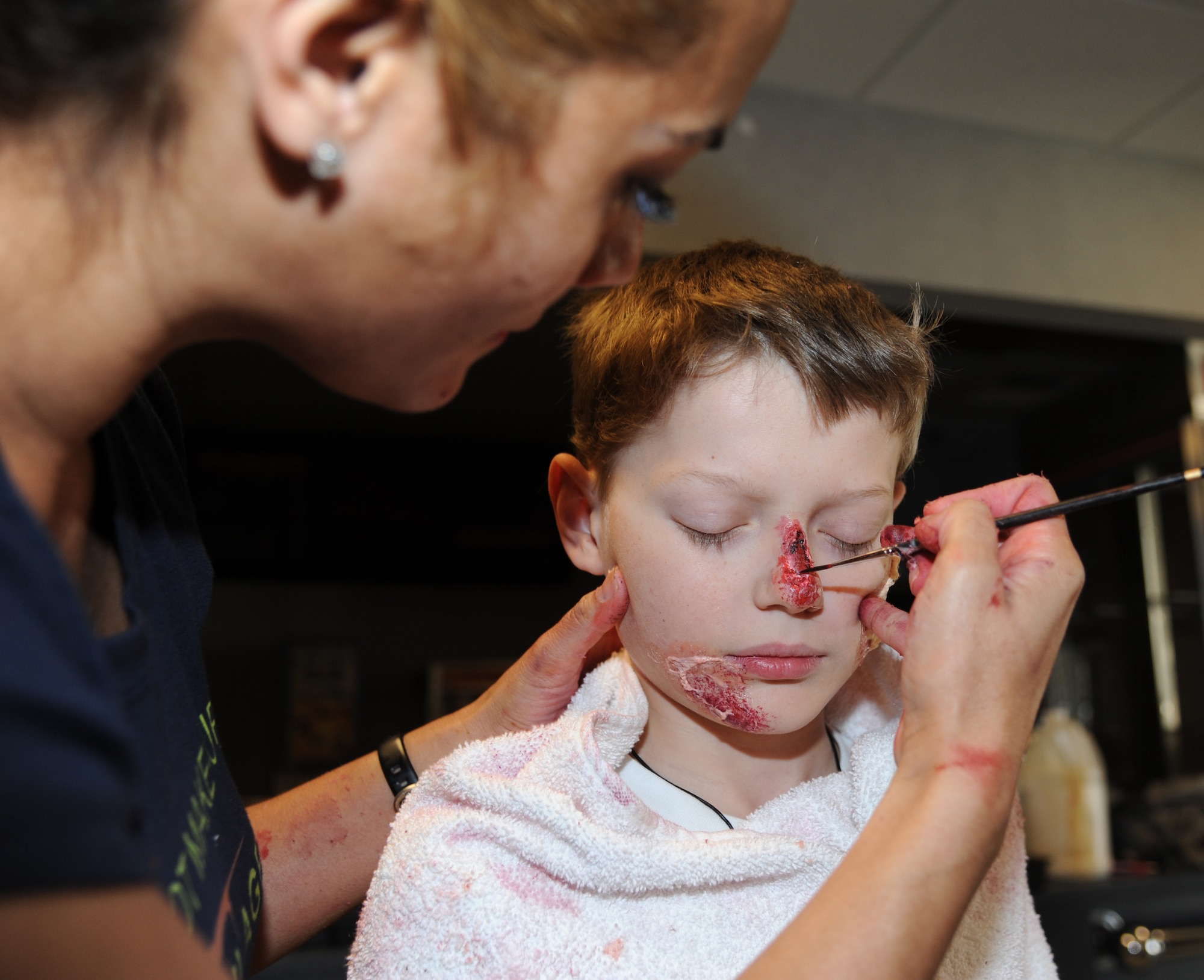 Caroline Bunce, 81st Dental Squadron, applies moulage on Jordan Barker, 10, son of Maj. Amber Barker, 81st Medical Group, as he plays a “victim” of anthrax exposure during a disease containment plan and point of dispensing exercise Feb. 28, 2013, near the Vandenburg Community Center, Keesler Air Force Base, Miss.  The scenario included a series of biological attacks in which numerous Keesler personnel became infected and the medical group had to distribute large quantities of medicine to efficiently minimize risk. (U.S. Air Force photo by Kemberly Groue)