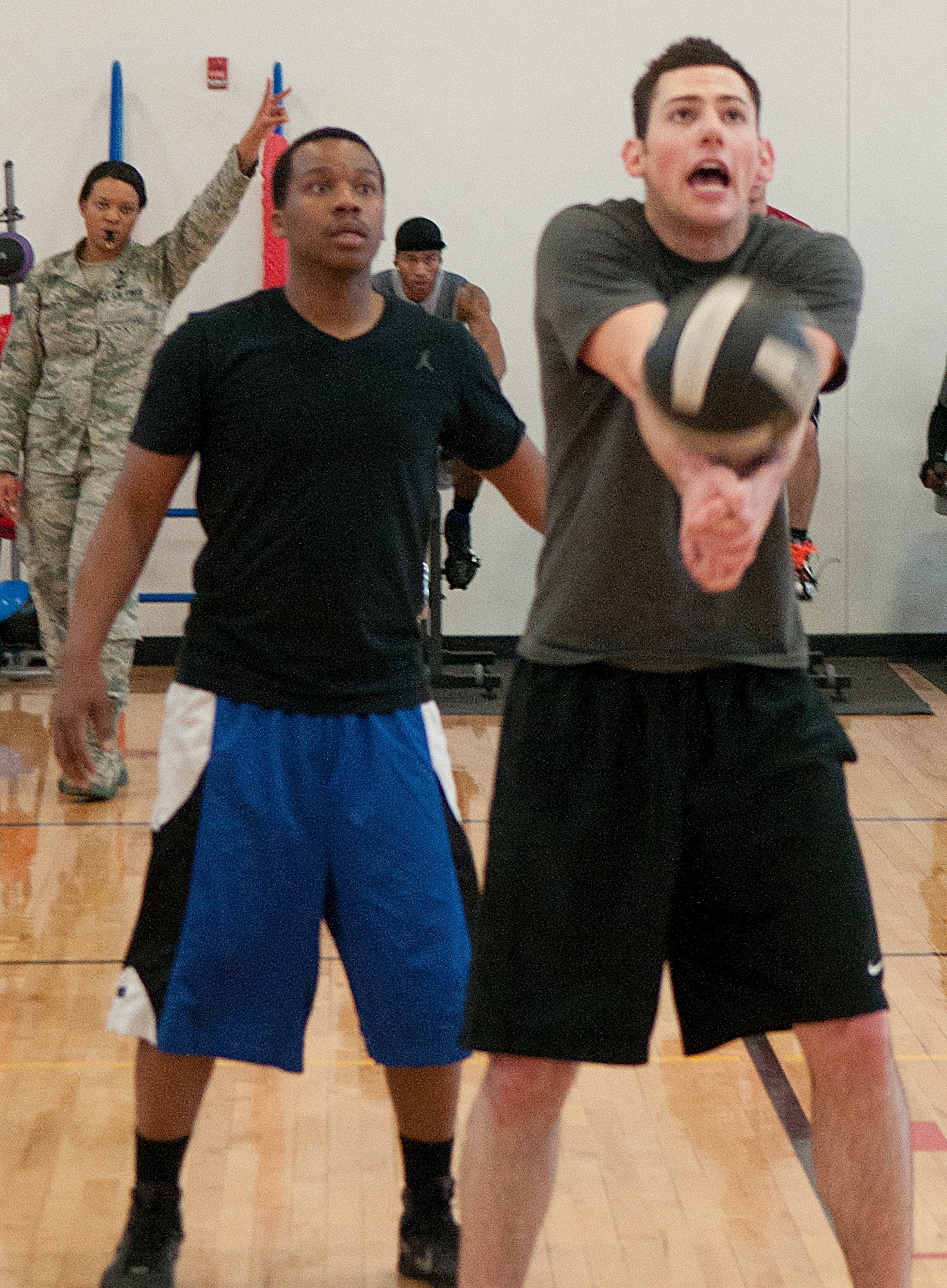 Danny Ermis sets up the ball for his 90th Missile Maintenance Group teammates during a volleyball game against 90th Comptroller Squadron during a tournament at Freedom Hall Fitness Center on F. E. Warren Air Force Base Feb. 23, as Everette Gains looks on. (U.S. Air Force photo by R.J. Oriez)