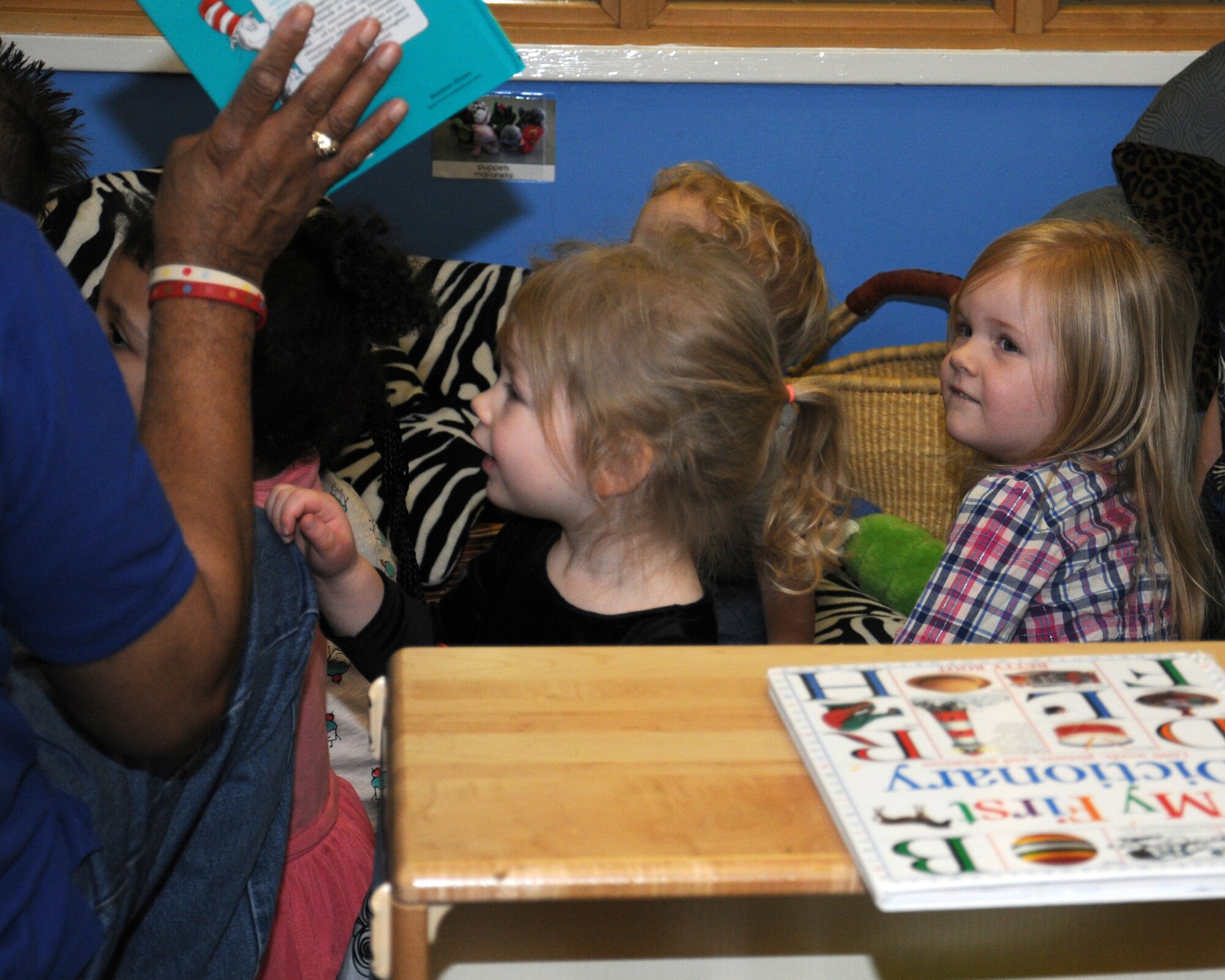 Barron Turner, left, child development center worker, reads a Dr. Seuss' book to children March 1, 2013, at the child development center on RAF Mildenhall, England. March 1 is Read Across America Day, which is a nationwide observance coinciding with the birthday of Dr. Seuss Geisel, the author of many popular children's books. In 1997, the National Education Association pushed for a special day to celebrate reading throughout the United States. This idea proved to be a popular one; the first Read Across America Day was held March 2, 1998. (U.S. Air Force photo by Gina Randall/Released)