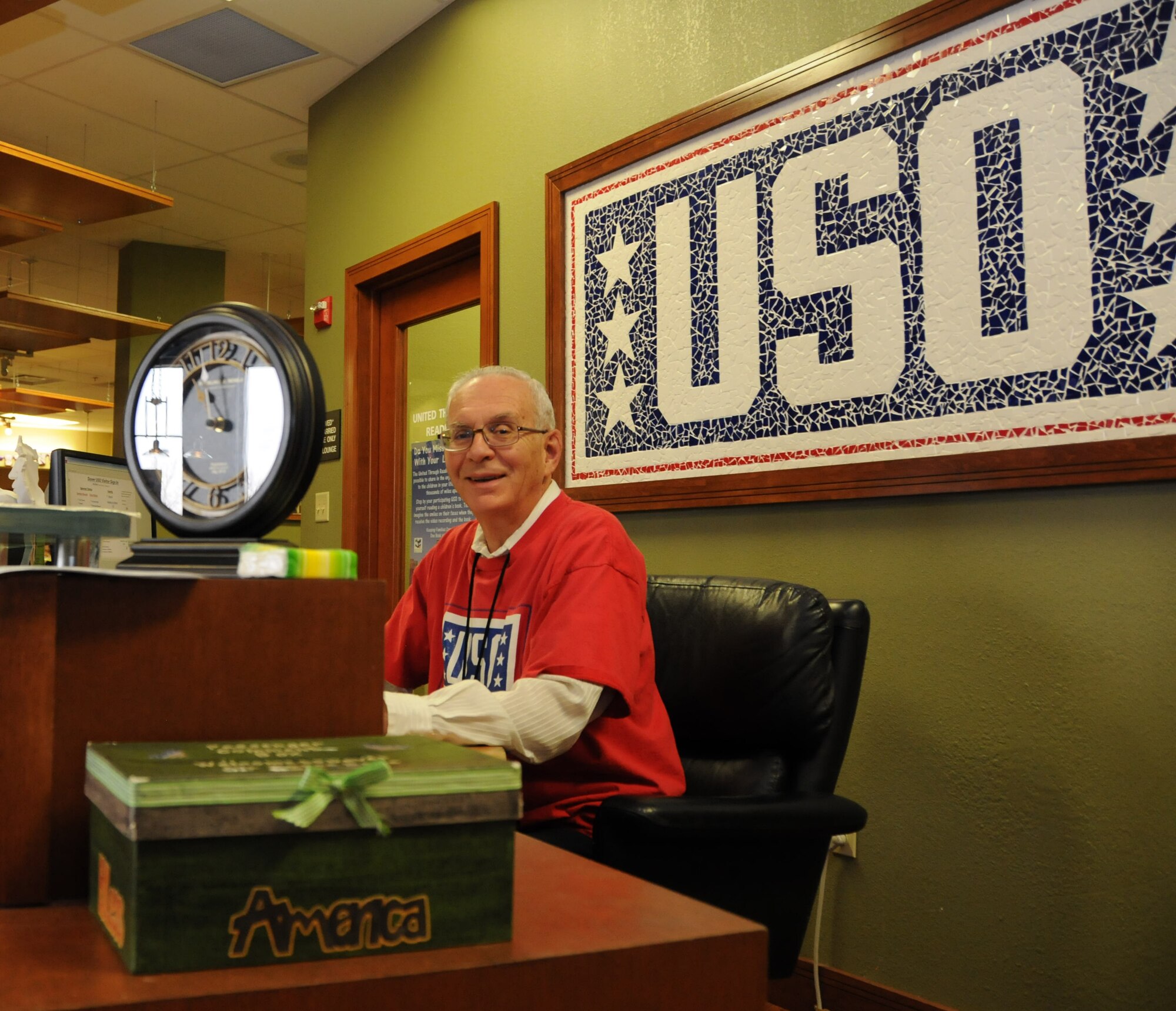 USO volunteer John Guy sits at a welcome desk where he greets visitors and their families at the USO Delaware center Feb. 22, 2013. The number of USO Delaware active volunteers has more than doubled in the past two and a half years. (U.S. Air force photo by Senior Airman Joe Yanik/Released)