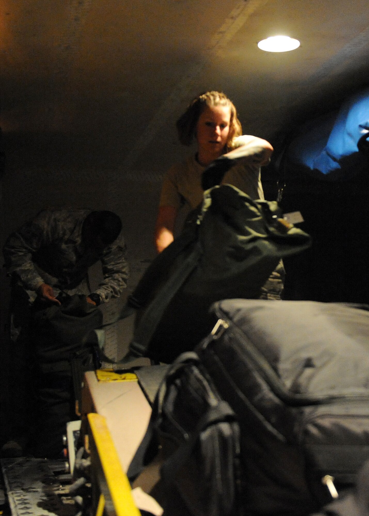 SOUTHWEST ASIA - Airman 1st Class Genny Martin, 8th Expeditionary Air Mobility Squadron, unloads baggage from a plane that just landed Feb. 27. When the aircraft arrives, the air terminal team has personnel standing by to operate baggage conveyors, staircase trucks and buses. In the past year, 8th EAMS Air Terminal moved more than 3,500 tons of baggage. Martin is deployed from the 721st Aerial Port Squadron at Ramstein Air Base, Germany. (U.S. Air Force photo/Senior Airman Joel Mease)