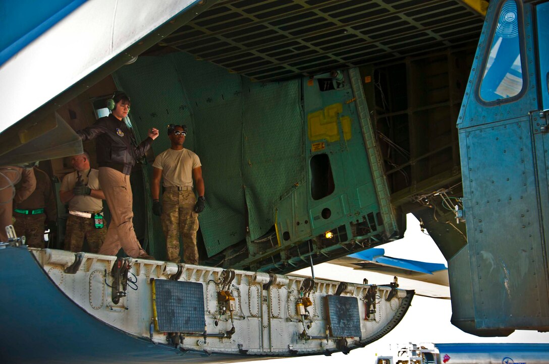 (Right) Senior Airman Pascal Felder, 451st Expeditionary Logistics Readiness Squadron aeral porter, looks on while a C-5 Galaxy loadmaster guides a Tunner 60K aircraft cargo loader at Kandahar Airfield, Afghanistan, Feb. 23, 2013. Felder is deployed from the Alaska Air National Guard 176th Wing. (U.S. Air Force photo/Senior Airman Scott Saldukas)