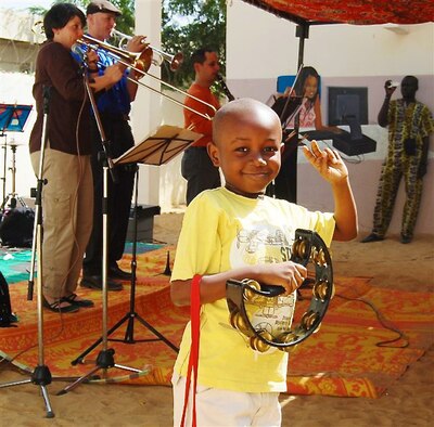 An N’Djamena International English School student holds a tambourine and displays the peace sign while the Wings of Dixie ensemble of the U.S.  Air Forces in Europe-Air Forces Africa Band perform at the school located in N’Djamena, Chad Feb 20, 2013. The performance was one of five the Band held during a weeklong visit to the African nation in support of USAFE-AFAFRICA’s Building Partnership Initiative. The Band performed at numerous locations including the University of N’Djamena and the U.S. Embassy in N’Djamena. U.S. Air Force Courtesy Photo