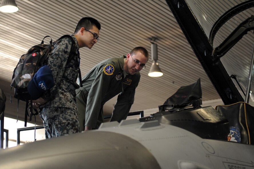 U.S. Air Force 1st Lt. Preston Phillips, right, 610th Air Control Flight air weapons officer, and 1st Lt. Kento Yoshida, Japan Air Self-Defense Force command and control officer, look in the cockpit of an F-16 Fighting Falcon during a JASDF-U.S. Officer Exchange Day at Misawa Air Base, Japan, Feb. 28, 2013. Events for the day included tours of a Navy P-3 aircraft and F-16 Fighting Falcon, as well as an F-16 load demonstration and trying out the hypoxia training system. (U.S. Air Force photo by Airman 1st Class Kia Atkins)
