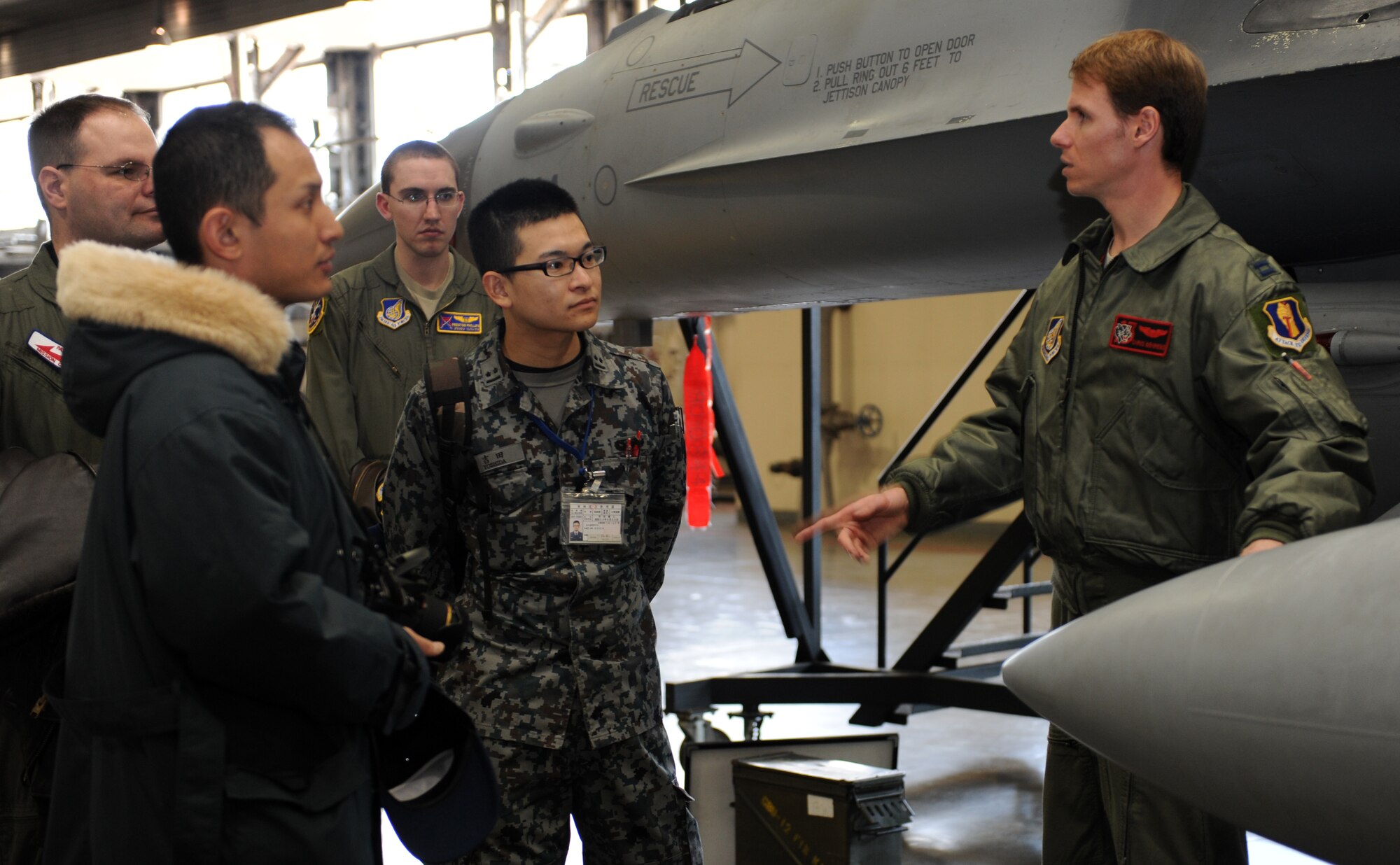 U.S. Air Force Capt. Chris Behrens, right, 35th Operations Support Squadron wing weapons and tactics flight commander, talks to fellow officers from the Air Force, Navy and Japan Air Self-Defense Force about the F-16 Fighting Falcon aircraft’s specifications during a JASDF-U.S. Officer Exchange Day at Misawa Air Base, Japan, Feb. 28, 2013. The purpose of the event was to expand relationships between the JASDF, Air Force and Navy by showing what each service does on a daily basis. (U.S. Air Force photo by Airman 1st Class Kia Atkins)
