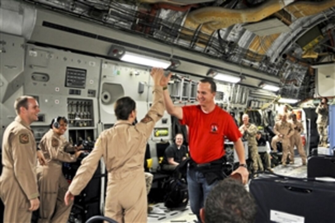 Denver Broncos quarterback Peyton Manning congratulates U.S. Air Force Staff Sgt. Christine Myers after she catches a pass from him aboard a C-17 Globemaster aircraft en route to Afghanistan, March 1, 2013, during the USO spring tour. U.S. Navy Adm. James A. Winnefeld Jr., vice chairman of the Joint Chiefs of Staff, hosted the tour.