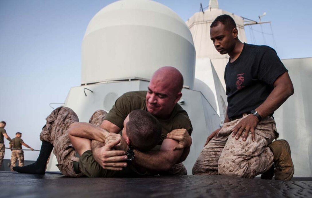 Sergeant Brandon Gibson, 15th Marine Expeditionary Unit, supervises Marines participating in a grappling match during Corporals' Course aboard the USS Green Bay, Feb. 26. Corporals' Course is professional military education for enlisted Marines designed to give them the tools to become effective small unit leaders. The 15th MEU is deployed as part of the Peleliu Amphibious Ready Group as a U.S. Central Command theater reserve force, providing support for maritime security operations and theater security cooperation efforts in the U.S. 5th Fleet area of responsibility. (U.S. Marine Corps photo by Cpl. Bobby J. Gonzalez/Released)