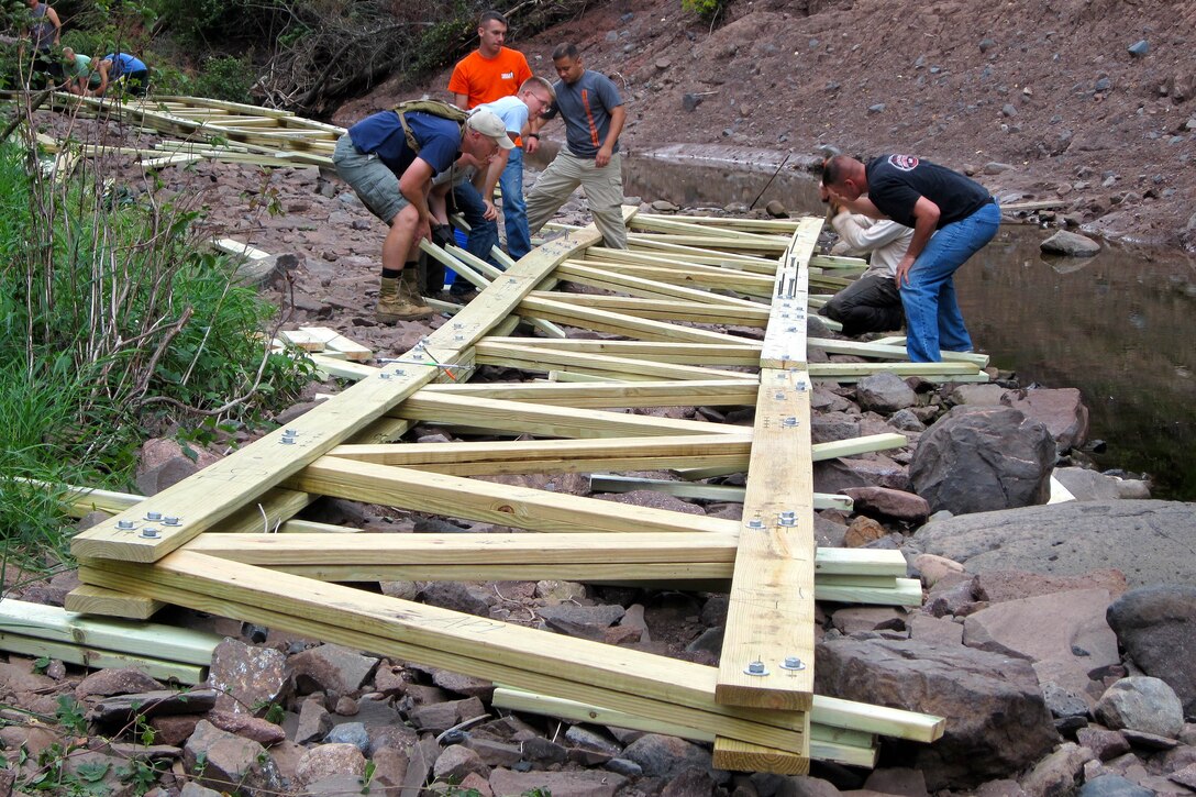 Volunteers from Marine Wing Support Squadron 471 reconstruct the 54-foot Encampment River Bridge from scratch along the Superior Hiking Trail Sept. 7. Flood waters washed the structure away two months prior.