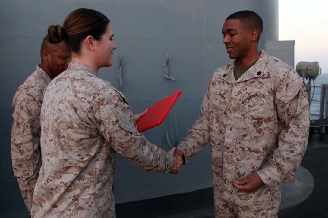 Newly promoted Staff Sgt. Mack A. Clater, administrative specialist, shakes hands with Capt. Janine Mills, adjutant, both with the Command Element, 15th Marine Expeditionary Unit, after Clater received his new rank on the USS Peleliu, March 1. The 15th MEU is deployed as part of the Peleliu Amphibious Ready Group as a U.S. Central Command theater reserve force, providing support for maritime security operations and theater security cooperation efforts in the U.S. 5th Fleet area of responsibility. Clater, 27, is from Hallsburg, Texas. (U.S. Marine Corps photo by Cpl. John Robbart III/Released)