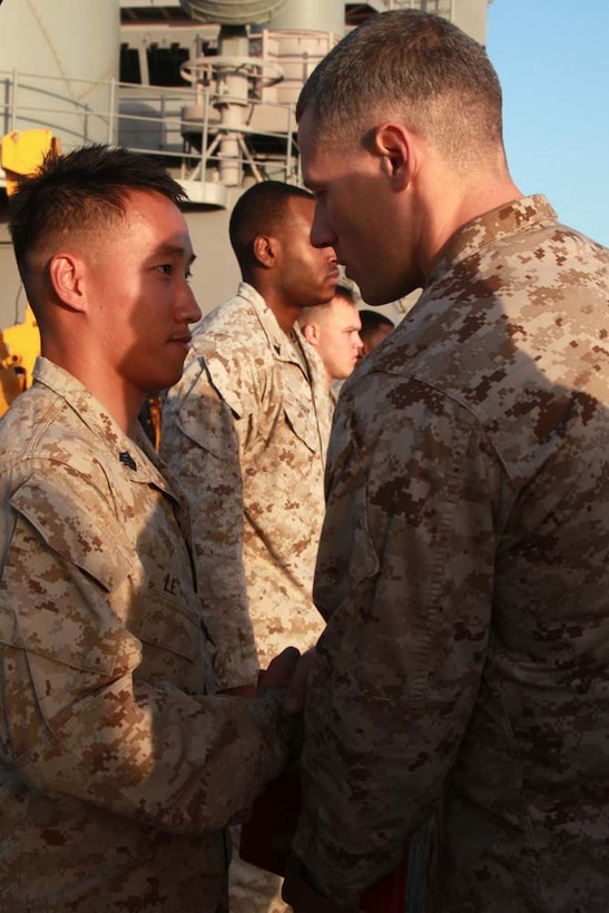 Newly promoted Sgt. Hung X. Le, electronic key management system operator, Headquarters and Service Company, Battalion Landing Team 3/5, 15th Marine Expeditionary Unit, shakes hands with Capt. Braxton Mashburn, his commanding officer, after receiving his new rank on the flight deck of the USS Peleliu, March 1. The 15th MEU is deployed as part of the Peleliu Amphibious Ready Group as a U.S. Central Command theater reserve force, providing support for maritime security operations and theater security cooperation efforts in the U.S. 5th Fleet area of responsibility. Le, 21, is from Houston. (U.S. Marine Corps photo by Cpl. John Robbart III/Released)