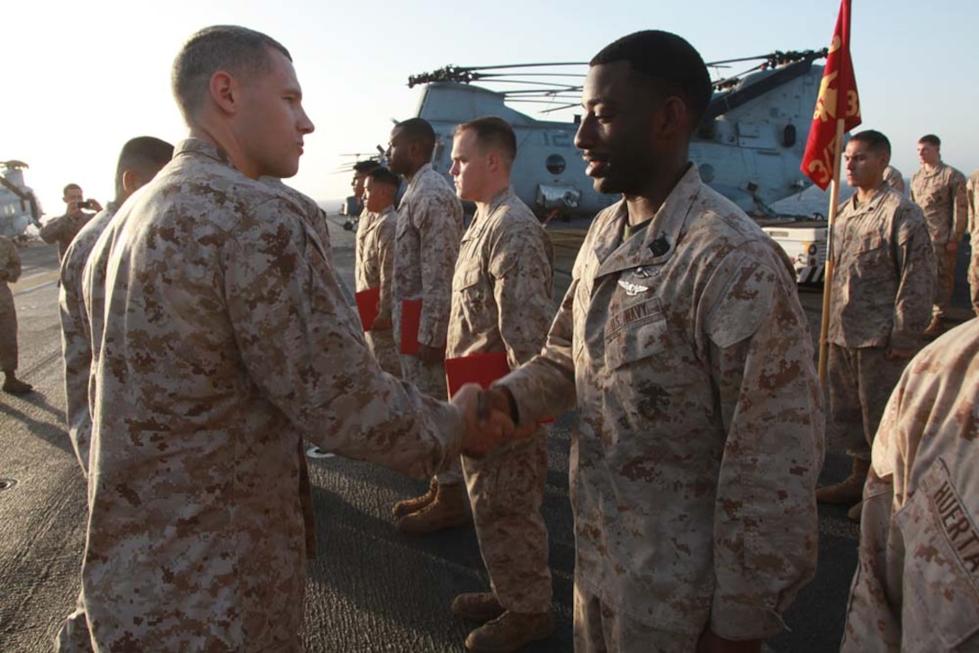 Hospital Corpsman 2nd Class Andre A. Tyree, physical therapist technician, Headquarters and Service Company, Battalion Landing Team 3/5, 15th Marine Expeditionary Unit, shakes hands with Capt. Braxton Mashburn, his commanding officer, after receiving his Air Warfare pin on the flight deck of the USS Peleliu, March 1. The 15th MEU is deployed as part of the Peleliu Amphibious Ready Group as a U.S. Central Command theater reserve force, providing support for maritime security operations and theater security cooperation efforts in the U.S. 5th Fleet area of responsibility. Tyree, 25, is from St. Matthews, S.C. (U.S. Marine Corps photo by Cpl. John Robbart III/Released)