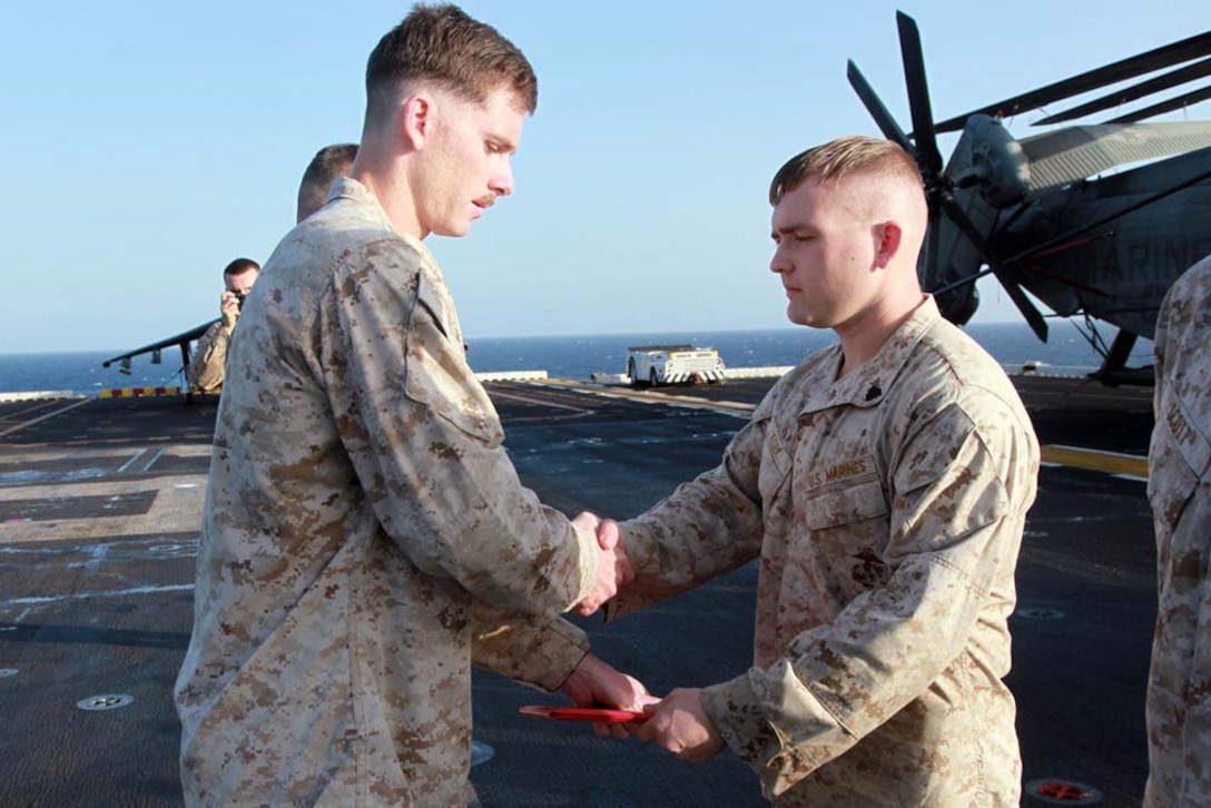Newly promoted Sgt. Nathaniel W. Kiser, combat engineer, Combat Engineer Platoon, Battalion Landing Team 3/5, 15th Marine Expeditionary Unit, receives his promotion warrant from 1st Lt. Kyle P. McCarley, his platoon commander, after being promoted to his present rank on the flight deck of the USS Peleliu, March 1. The 15th MEU is deployed as part of the Peleliu Amphibious Ready Group as a U.S. Central Command theater reserve force, providing support for maritime security operations and theater security cooperation efforts in the U.S. 5th Fleet area of responsibility. Kiser, 23, is from New Palestine, Ind. (U.S. Marine Corps photo by Cpl. John Robbart III/Released)