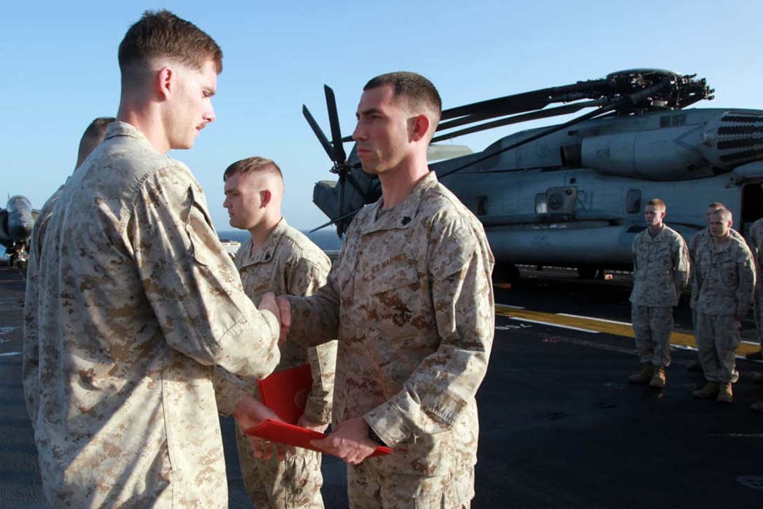 Newly promoted Sgt. Travis J. Scott, combat engineer, Combat Engineer Platoon, Battalion Landing Team 3/5, 15th Marine Expeditionary Unit, receives his promotion warrant from 1st Lt. Kyle P. McCarley, his platoon commander, after being promoted to his present rank on the flight deck of the USS Peleliu, March 1. The 15th MEU is deployed as part of the Peleliu Amphibious Ready Group as a U.S. Central Command theater reserve force, providing support for maritime security operations and theater security cooperation efforts in the U.S. 5th Fleet area of responsibility. Scott, 28, is from New Paltz, N.Y. (U.S. Marine Corps photo by Cpl. John Robbart III/Released)