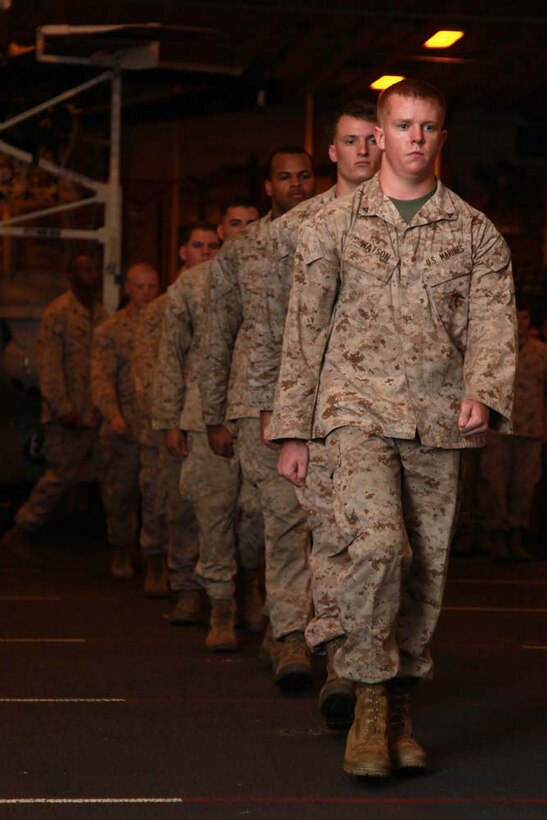 Marines and sailors with Marine Medium Helicopter Squadron 364 (Rein.), 15th Marine Expeditionary Unit, march to the front of a formation before receiving awards in the hangar bay of the USS Peleliu, March 1. The 15th MEU is deployed as part of the Peleliu Amphibious Ready Group as a U.S. Central Command theater reserve force, providing support for maritime security operations and theater security cooperation efforts in the U.S. 5th Fleet area of responsibility. (U.S. Marine Corps photo by Cpl. John Robbart III/Released)