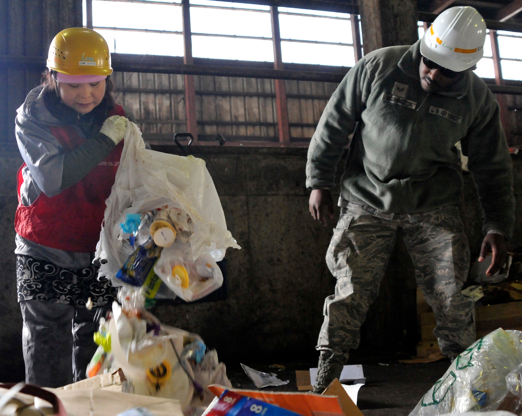 Kasumi Yamazaki, Hosoya Disposal Site assistant manager, pours out a bag of general waste found in a recyclables delivery, while U.S. Air Force Senior Airman David Washington, 35th Civil Engineer Squadron recycling manager, looks on in Misawa City, Japan, Feb. 28, 2013. Recycling managers from Misawa Air Base perform inspections at the disposal site to ensure proper recycling techniques are being followed. Hosoya is the final stop for all of the base’s trash and recyclables. (U.S. Air Force photo by Tech. Sgt. Phillip Butterfield) 