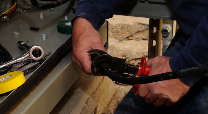 Ray O'Briant, 2nd Civil Engineer Squadron Heating, Ventilation, Air Conditioning, and Refrigeration, cuts power cables during modifications of a chiller on Barksdale Air Force Base, La., March 1. The previous chiller was an older model, so when the new chiller was installed, modifications to the power and pipe system had to be done in order for it to function properly. (U.S. Air Force photo/Airman 1st Class Andrew Moua)