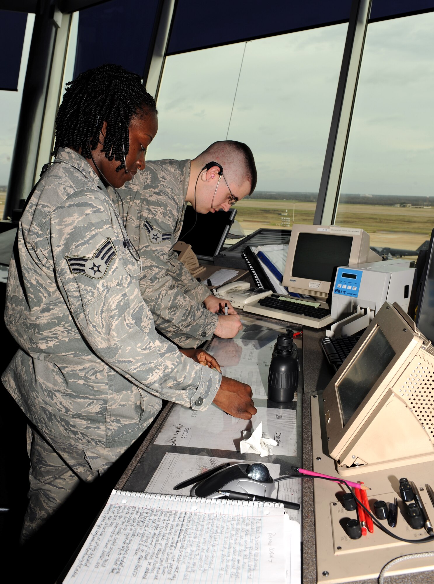Senior Airman Keona Woods and Airman 1st Class Bryan England, 2nd Operations Support Squadron Air Traffic Controllers, look at flight strips on Barksdale Air Force Base, La., March 4. The flight strips show the aircraft flight plan, including the aircraft departure time and destination. (U.S. Air Force photo/Airman 1st Class Benjamin Gonsier)