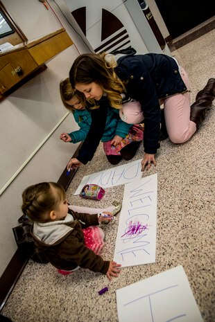 Kristin Pete, wife of Capt. Joshua Pete, 14th Airlift Squadron pilot, draws welcome home messages with her children during the 14th AS redeployment March 3, 2013, at Joint Base Charleston - Air Base, S.C. More than 100 Airmen from the 14th AS returned home from a 120-day deployment to Southwest Asia. (U.S. Air Force photo/ Senior Airman George Goslin)