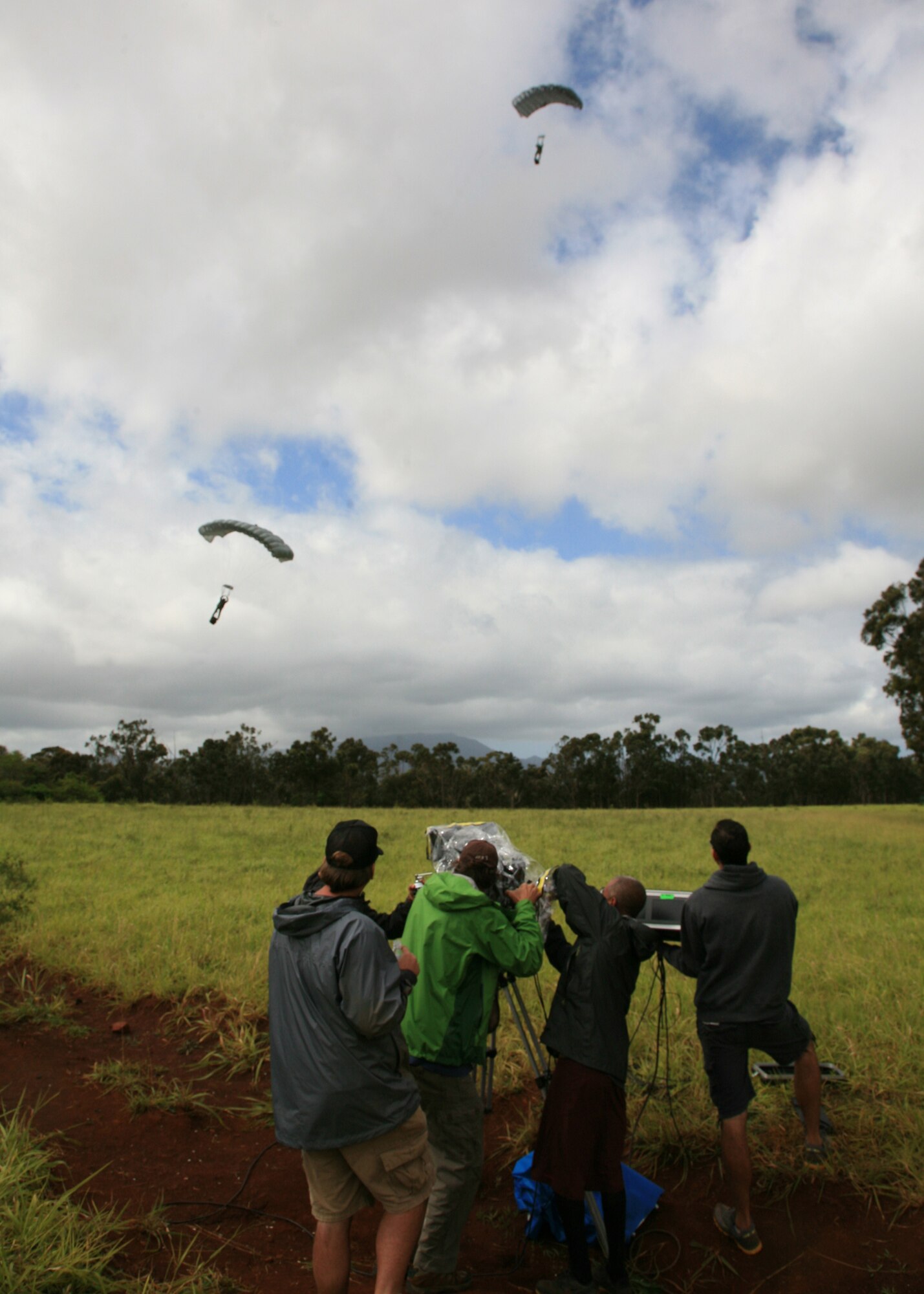 Members of the "Hawaii Five-0" production crew film the landing of Special Operations Command, Pacific freefall jumpers, Maj. Aaron Lawson, (left) and U.S. Marine Corps Staff Sgt. John Phillips (right), near Joint Base Pearl Harbor-Hickam, Hawaii, Feb. 26, 2013. Lawson and Phillips were given the opportunity to perform the jump from a C-17 Globemaster III as stunt doubles for "Hawaii Five-0" actors. The crew was on hand to film the jump for use in a scene for an upcoming episode. (Photo by Tom Sanders)