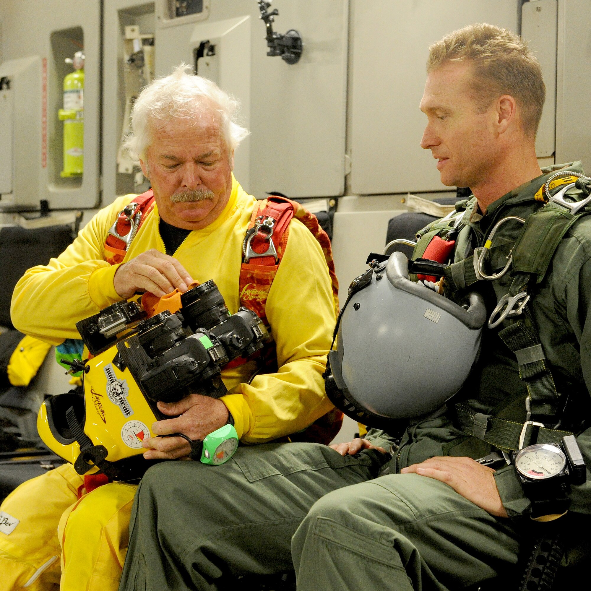 Tom Sanders, freefall cameraman and skydiver cinematographer (left), cleans his camera lens as he talks with Maj. Aaron Lawson, Special Operations Command, Pacific  jumper and special tactics officer (right), prior to taking off in a C-17 Globemaster III at Joint Base Pearl Harbor Hickam-Hawaii, Feb. 26, 2013. Lawson, who was given the opportunity to serve as a stunt double for “Hawaii Five-0” actor Alex O’Loughlin, was accompanied by veteran cinematographer, Sanders, to film his freefall jump scene for an upcoming episode of the show. (U.S. Air Force photo/Tech. Sgt. Jerome S. Tayborn)