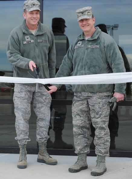 Col. Bruce Roehm, 341st Medical Group Commander (left), and Col. Robert Stanley, 341st Missile Wing commander, cut the ribbon for the reopening of the main entrance of the clinic Feb. 25. Four years in the making, the initiative to replace the rotating entrance with sliding doors was the result of a collaborative effort of Air Force Health Facilities and the clinic staff. The combination of heated vestibules and slider doors now ensure a warmer waiting area for patients in the pharmacy. (U.S. Air Force photo/Airman 1st Class Katrina Heikkinen)
