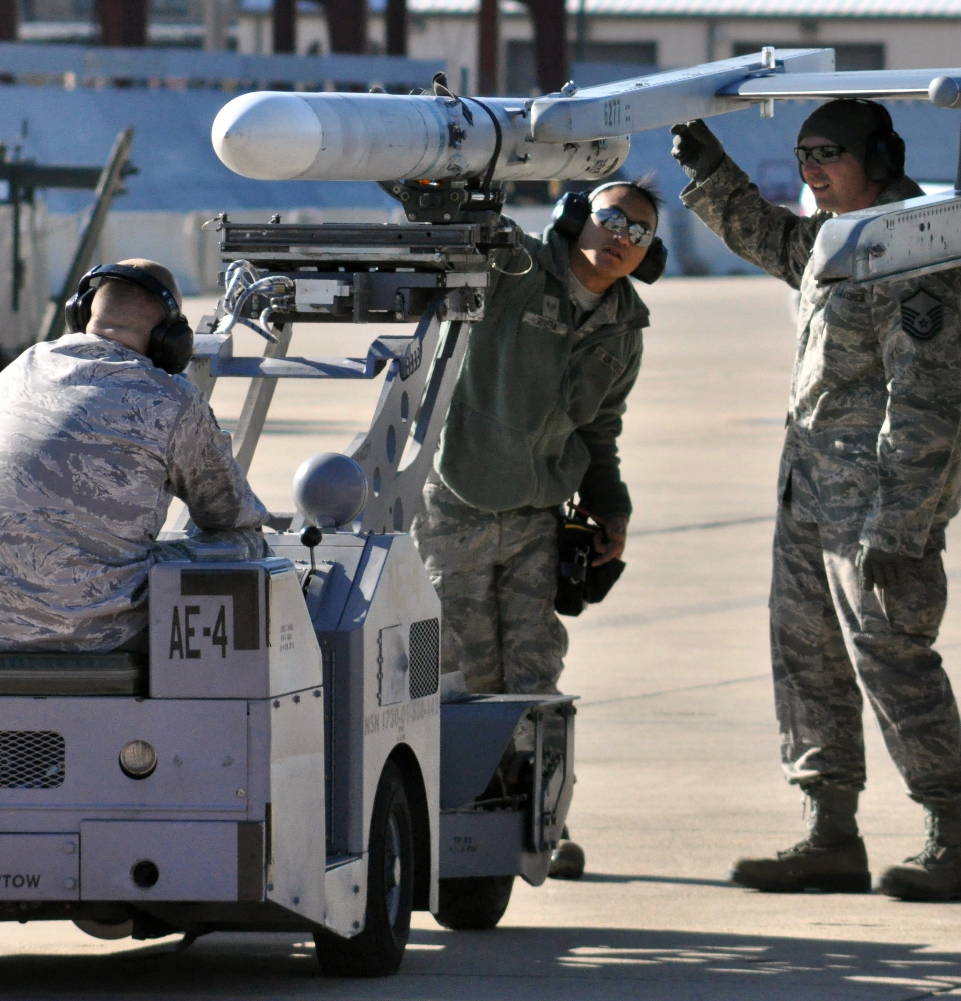 Staff Sgt. Wilfredo Rivera, Jr., load team member (center), and Master Sgt. David Hatton, load team chief (right), direct Staff Sgt. Jeffrey Irby, load team member, as he positions the weapons loader to lift and align a missile for placement on the 301st Fighter Wing's F-16 wing tip station. All load team members are Air Force Reservists assisgned to the 301st Aircraft Maintenance Squadron at the Naval Air Station Fort Worth Joint Reserve Base, Texas. (U.S. Air Force photo/Tech. Sgt. Chris Bolen) 