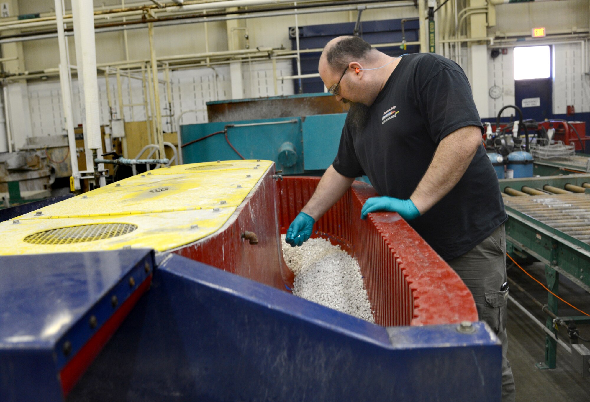 Andrew Haney, a blaster in the Vibratory Clean shop with the 548th Propulsion Maintenance Squadron, inspects parts going through the vibratory machine. (Air Force photos by Kelly White)
