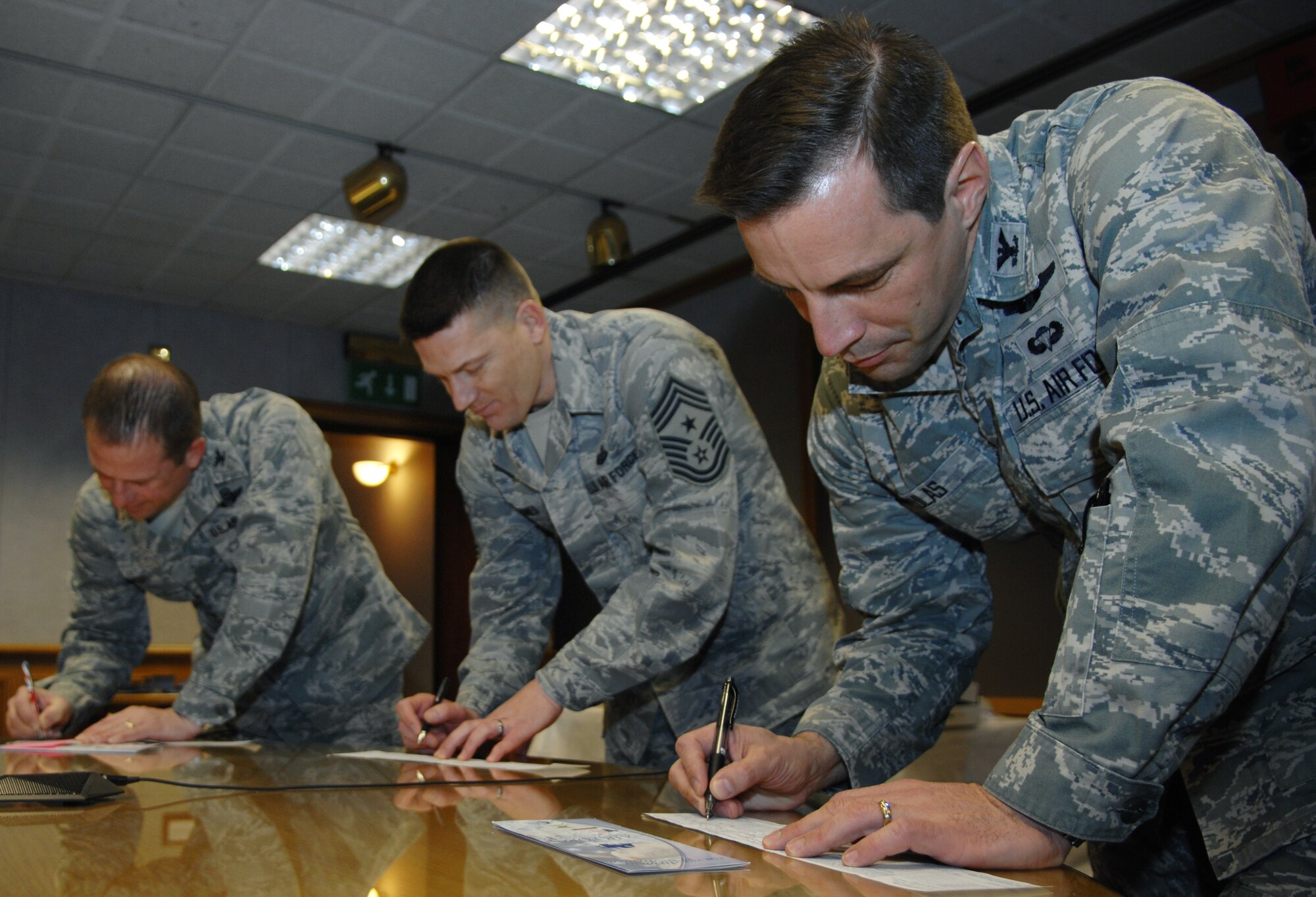 From right, Col. Christopher Kulas, 100th Air Refueling Wing commander, Chief Master Sgt. Tracy Jones, 100th ARW command chief, and Col. Kyle Voigt, 100th ARW vice commander, sign Air Force Assistance Fund donation slips during the AFAF kickoff March 4, 2013, at RAF Mildenhall, England. The AFAF campaign supports four charities that are dedicated to caring for Airmen from induction through retirement and beyond.  RAF Mildenhall’s goal for 2013 is to raise more than $60,000. (U.S. Air Force photo by Airman 1st Class Dillon Johnston/Released)
