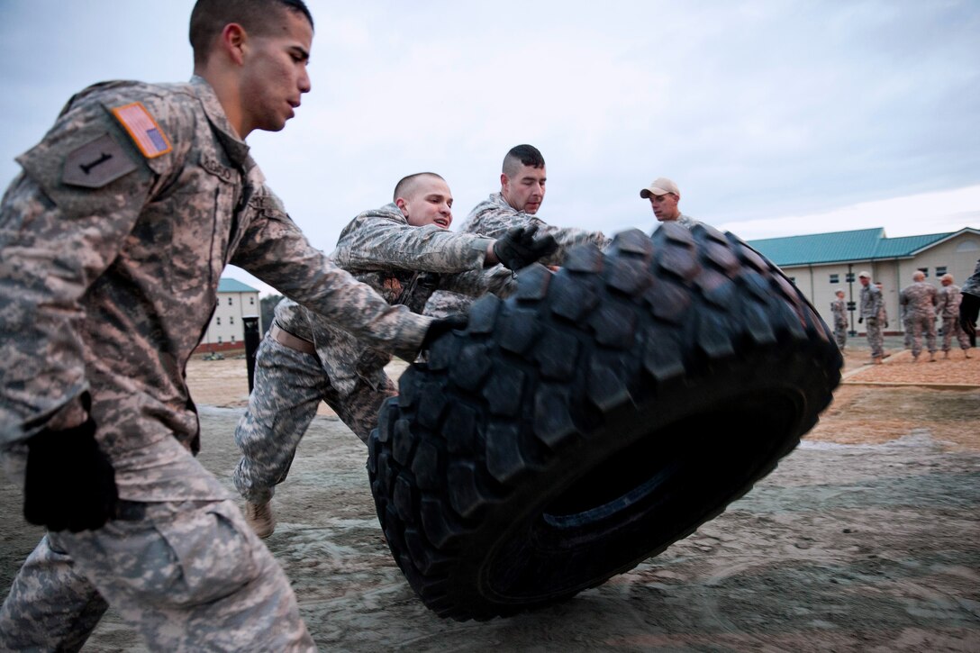 Army Pfc. Christopher Delgado, left, Pfc. Tanner Lewandowsky, center, and Staff Sgt. Logan Johnson flip a tire during the first Gainey Cup scout competition on Fort Benning, Ga., March 2, 2013. Delgado, Lewandowsky and Johnson are assigned to the 1st Infantry Division.