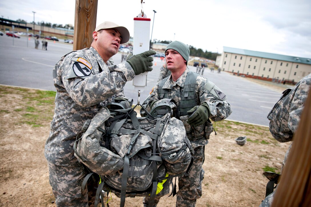 Army Spc. Travis Reis watches as a soldier weighs his ruck sack to validate the 35-pound weight requirement for the five-mile march event during the first Gainey Cup scout competition on Fort Benning, Ga., March 2, 2013. Reis is assigned to the 1st Armored Division.