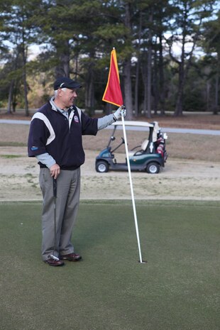 Bob Songer, a retired Col., gets ready to pull the flag out of the hole during the Big Game challenge at Paradise Point Golf Course aboard Marine Corps Base Camp Lejeune Feb. 3. The Big Game challenge is a modified 18-hole course played on the fairways and greens of The Scarlett golf course focused on honing player's short game before heading home for the super bowl.