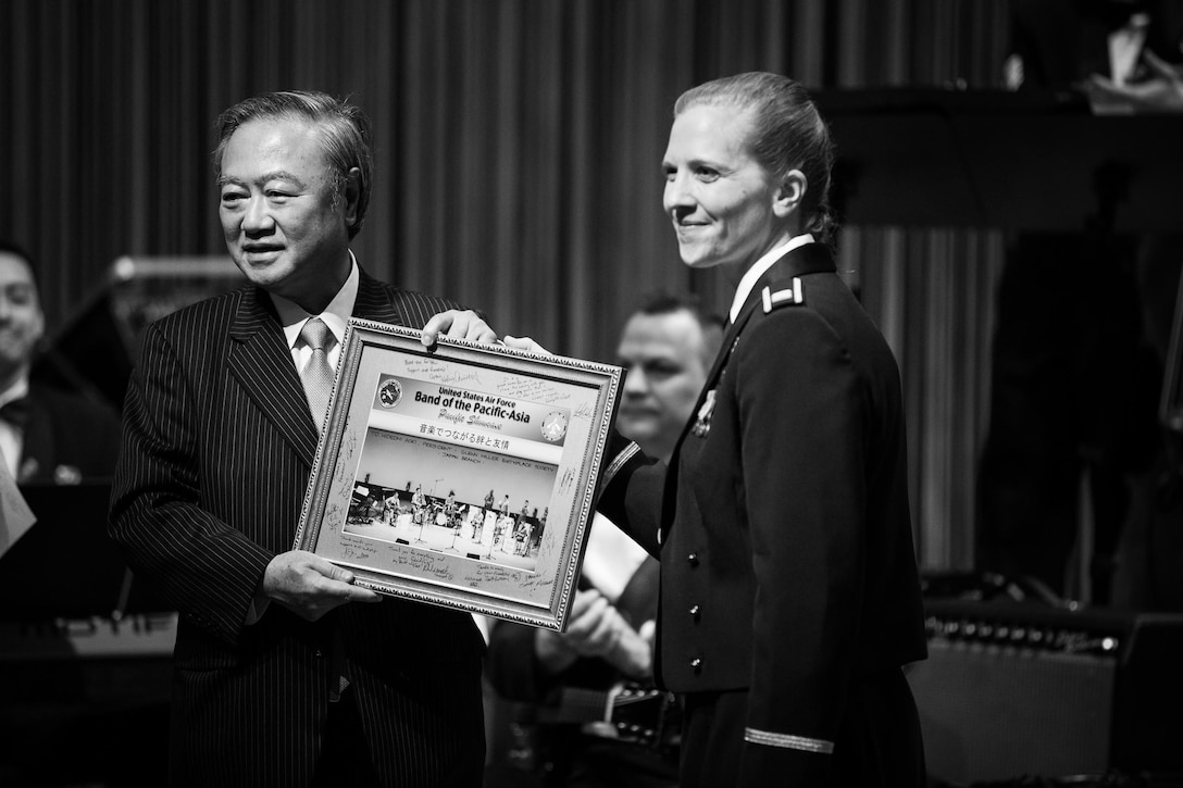 TOKYO, Japan -- Mr. Hideomi Aoki, Glenn Miller Birthplace Society Japan Branch president, accepts a token of appreciation presented by Capt. Haley Armstrong, U.S. Air Force Band of the Pacific-Asia commander, for sponsoring the band's performance at the society's 20th anniversary celebration, Tokyo American Club, Tokyo, Japan, March 1, 2013. The society's goals include developing the cultural relations between Japan and the U.S. and deepening a mutual understanding of both countries through the music of Glenn Miller. (U.S. Air Force photo by Staff Sgt. Josh Voyles)