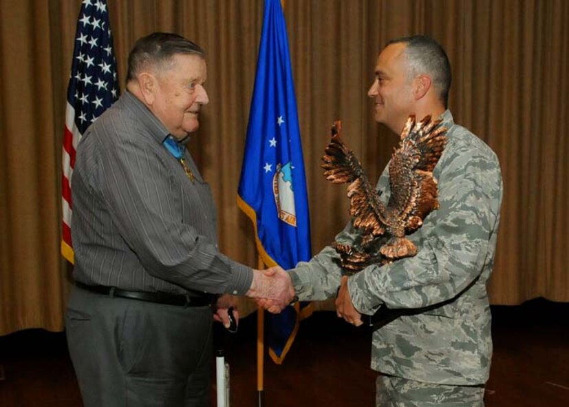 U.S. Air Force Medal of Honor recipient Col. (retired) Joe Jackson presents the Spirit Award to Lt. Col. David Hillman, 747th Communication Squadron commander, who accepts the award on behalf of the squadron, at the Memorial Theater, Joint Base Pearl Harbor-Hickam, Hawaii, Feb. 28, 2013. The 747th CS was received the award for showing the most motivation and team spirit during the 15th Wing’s promotion ceremony. (Photo by David Underwood)