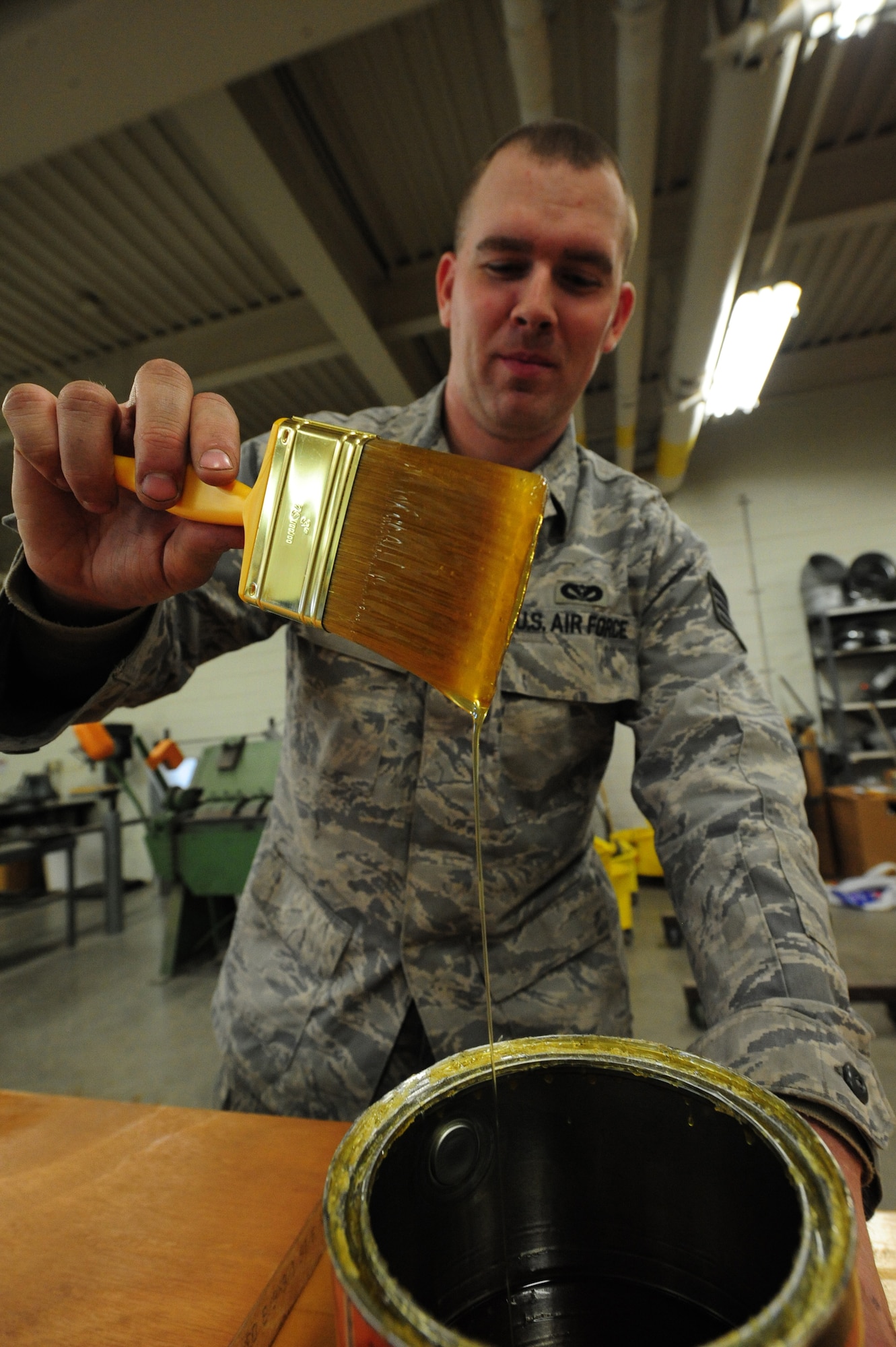 WHITEMAN AIR FORCE BASE, Mo. -- Staff Sgt. Adam Boyd, 509th Civil Engineer Squadron structural supervisor, dips a brush in polyurethane before polishing a wooden door, Feb. 27. The polyurethane prevents moisture from absorbing into the wood. (U.S. Air Force photo/Staff Sgt. Nick Wilson) (Released)
