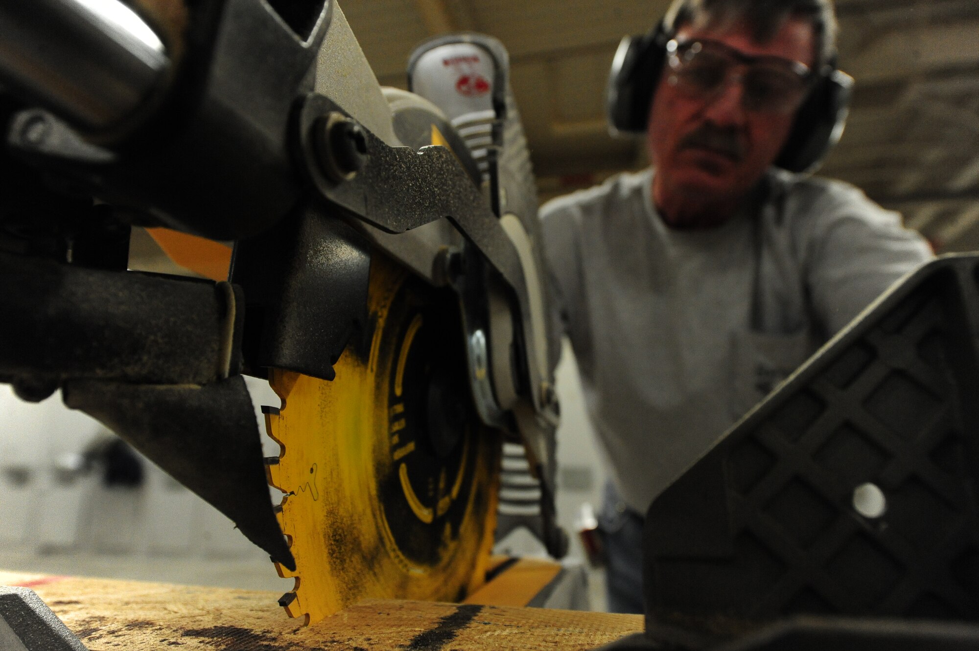 WHITEMAN AIR FORCE BASE, Mo. -- Albert Cote, 509th Civil Engineer Squadron carpenter, uses a compound miter saw to cut a piece of wood for a door frame, Feb. 27. The door frame will be used to repair a temporary lodging facility. (U.S. Air Force photo/Staff Sgt. Nick Wilson) (Released)