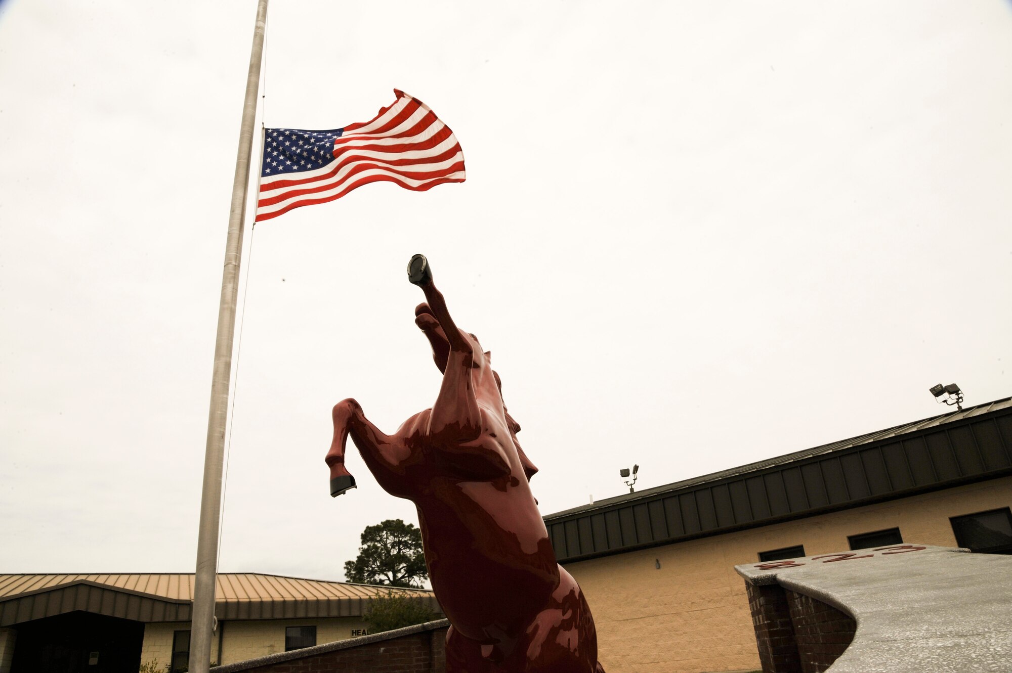 The 823rd RED HORSE Squadron flag stands at half-staff in honor of retired Brig. Gen. William Thomas Meredith.  The founding father or RED HORSE is responsible for the signature red hats.  “In the late 70’s, he believed that there was a need to distinguish [RED HORSE Airmen] from regular civil engineering units and have their own identifying mark,” said Staff Sgt. John Reece, pavements and construction operator of 823rd RHS.  (U.S. Air Force Photo by Airman 1st Class Benjamin D. Kim)