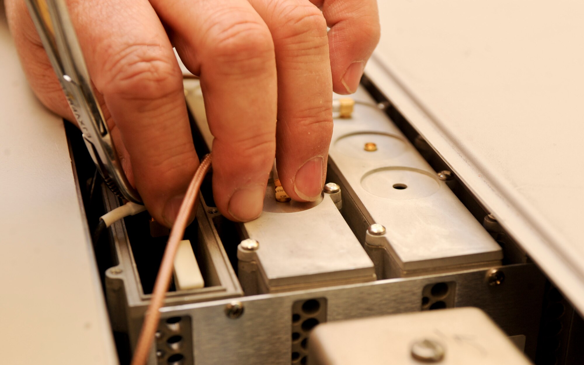 Tom Moeller, 28th Maintenance Squadron precision measurement equipment lab technician, removes a printed circuit assembly unit from an Anritsu 68347C synthesized signal generator after a calibration test at their lab on Ellsworth Air Force Base, S.D., Feb. 20, 2013. The printed circuit assembly unit was producing erratic frequencies and required a new circuit board. (U.S. Air Force photo by Airman 1st Class Anania Tekurio/Released)