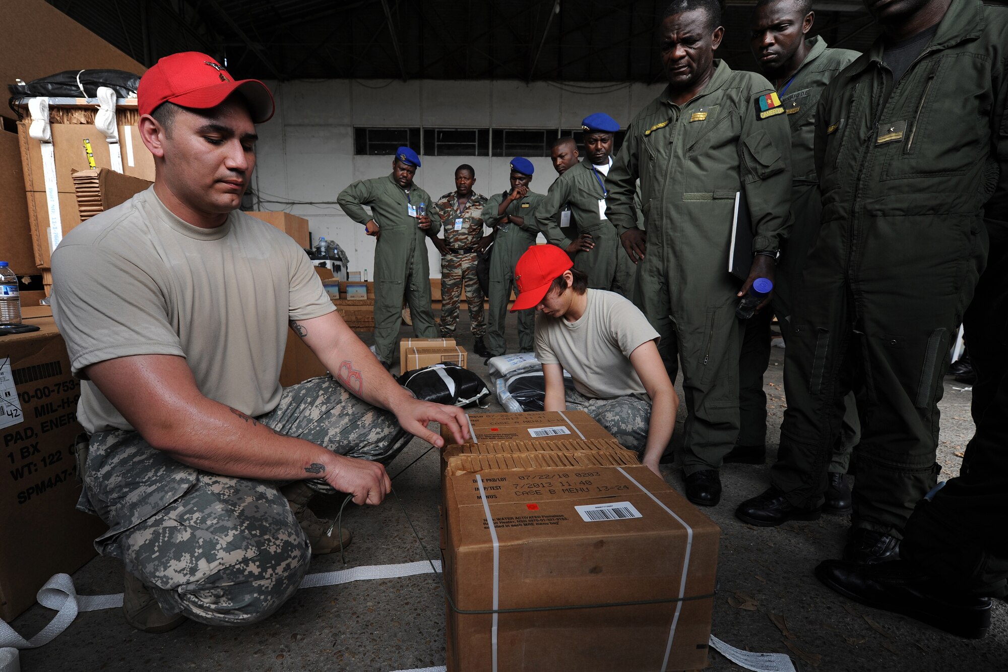 DOUALA, CAMEROON – U.S. Army Sergeant Jazmani Medina, a parachute rigger assigned to the 5th Quartermaster Battalion Detachment, Kaiserslautern, Germany, demonstrates how to build low-cost, low-altitude air drop bundles as Cameroon Air Force personnel look on during Central Accord 2013, at the Douala Air Force Base, Douala, Cameroon, February 22, 2013. Medina is participating in Central Accord 2013, a joint exercise in which U.S., Cameroon and neighboring Central African militaries partner to promote regional cooperation while and increasing aerial resupply and medical readiness capacity. (Photo by Master Sgt. MSgt Stan Parker, 621st CRW Public Affairs)