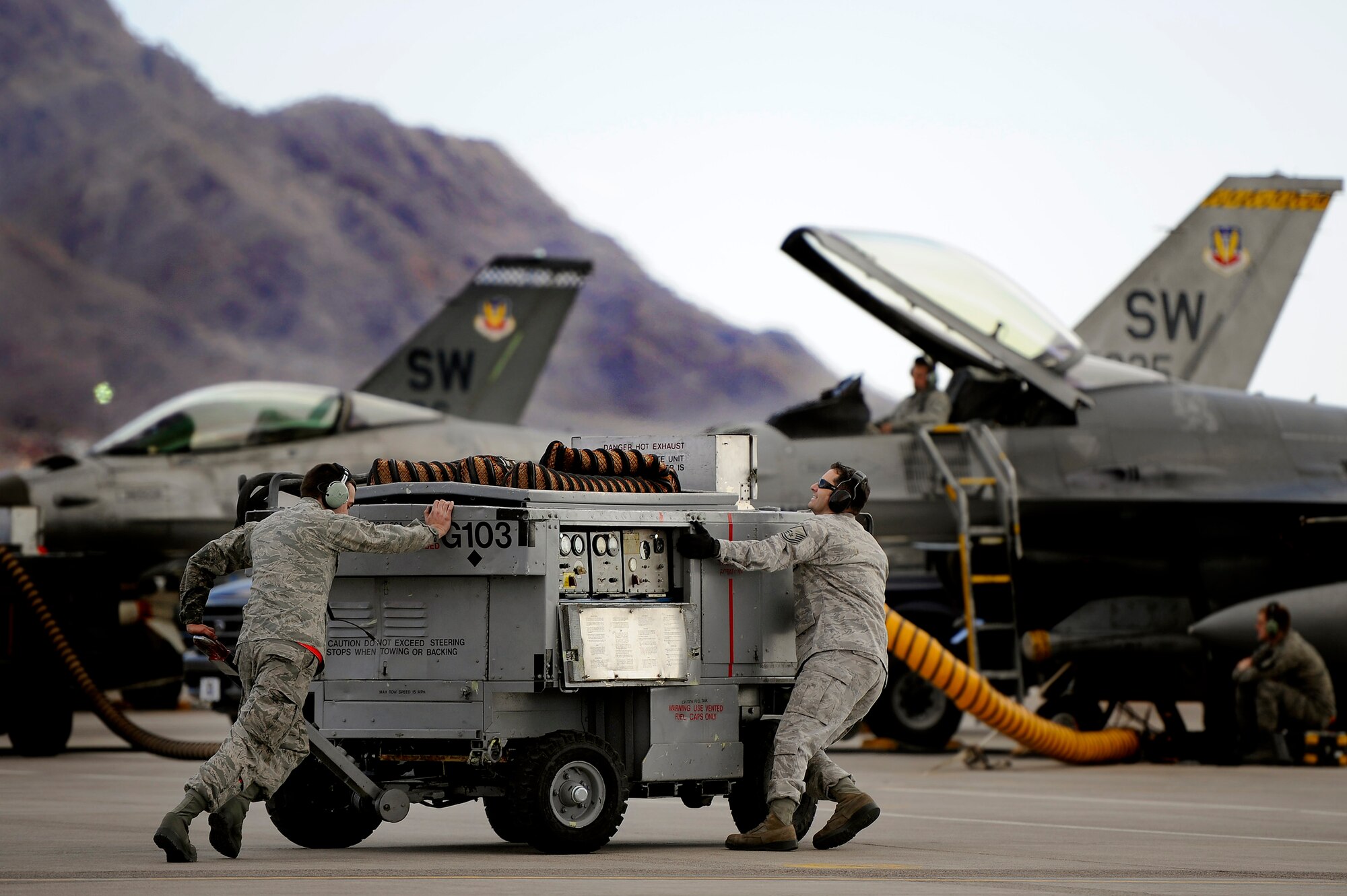 U.S. Air Force Senior Airman Mathew Wilcox, 20th Aircraft Maintenance Squadron (left) and Master Sgt. James Kennedy, 4th Aircraft Maintenance Squadron, work together to move aerospace ground equipment into position in order to prep 79th Fighter Squadron F-16 Fighting Falcons for takeoff during Red Flag 13-3, Feb. 23, 2013, Nellis Air Force Base, Nev. The 79th FS has 15 F-16 Fighting Falcons on the ground at Nellis AFB and 35 pilots slated to fly throughout the Red Flag exercise. (U.S. Air Force photo by Staff Sgt. Kenny Holston/Released)