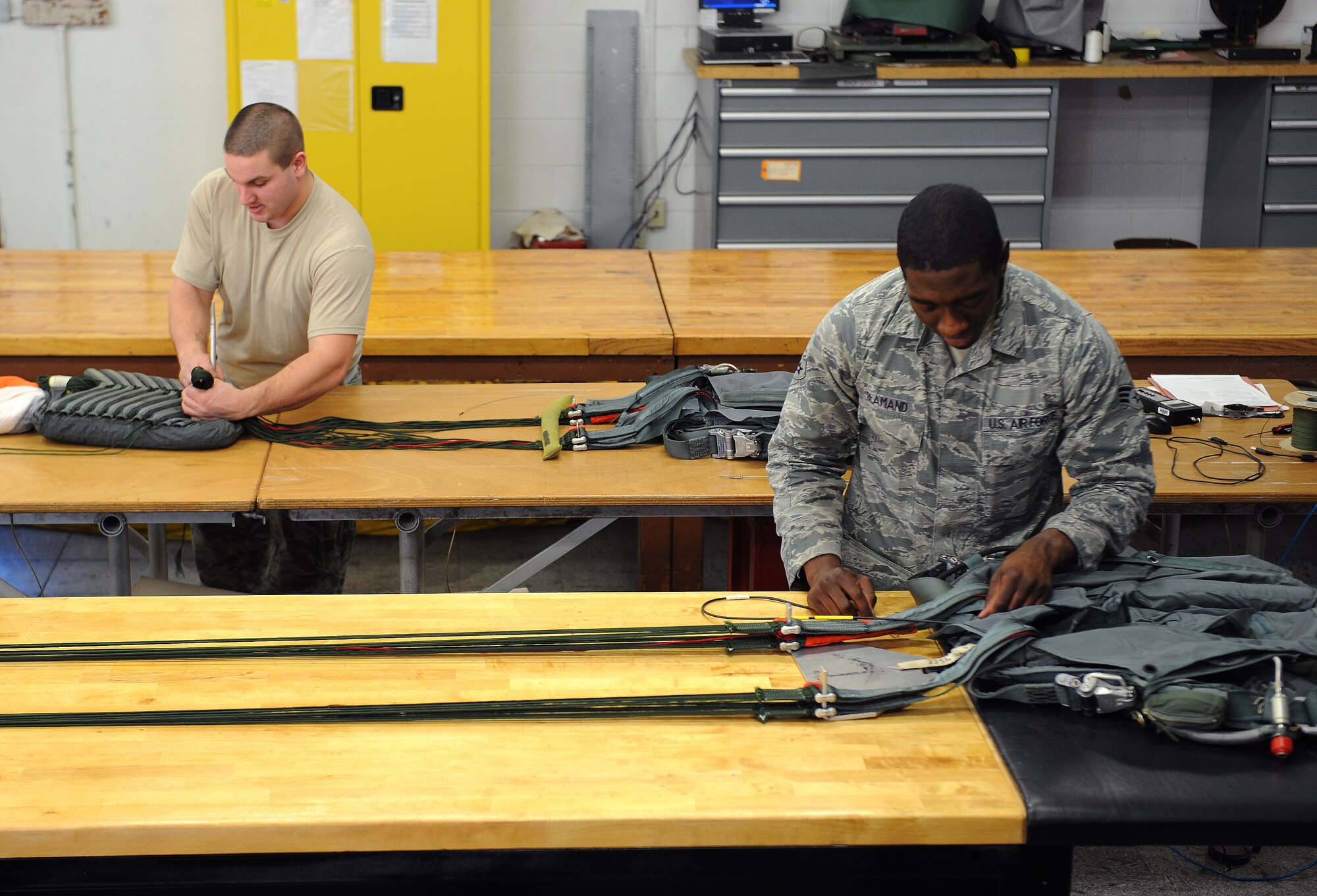 Senior Airman Kelly Adkins, left, stows chute lines into a quarter deployment bag as Senior Airman Ernest St. Amand, both from the 2nd Operations Support Squadron Aircrew Flight Equipment Parachute Shop, threads part of a back automatic parachute, BA-18, on Barksdale Air Force Base, La., March 5. The AFE parachute shop is in charge of packing, inspecting and supplying B-52H Stratofortress aircrew with their parachutes. (U.S. Air Force photo/Airman 1st Class Benjamin Gonsier)
