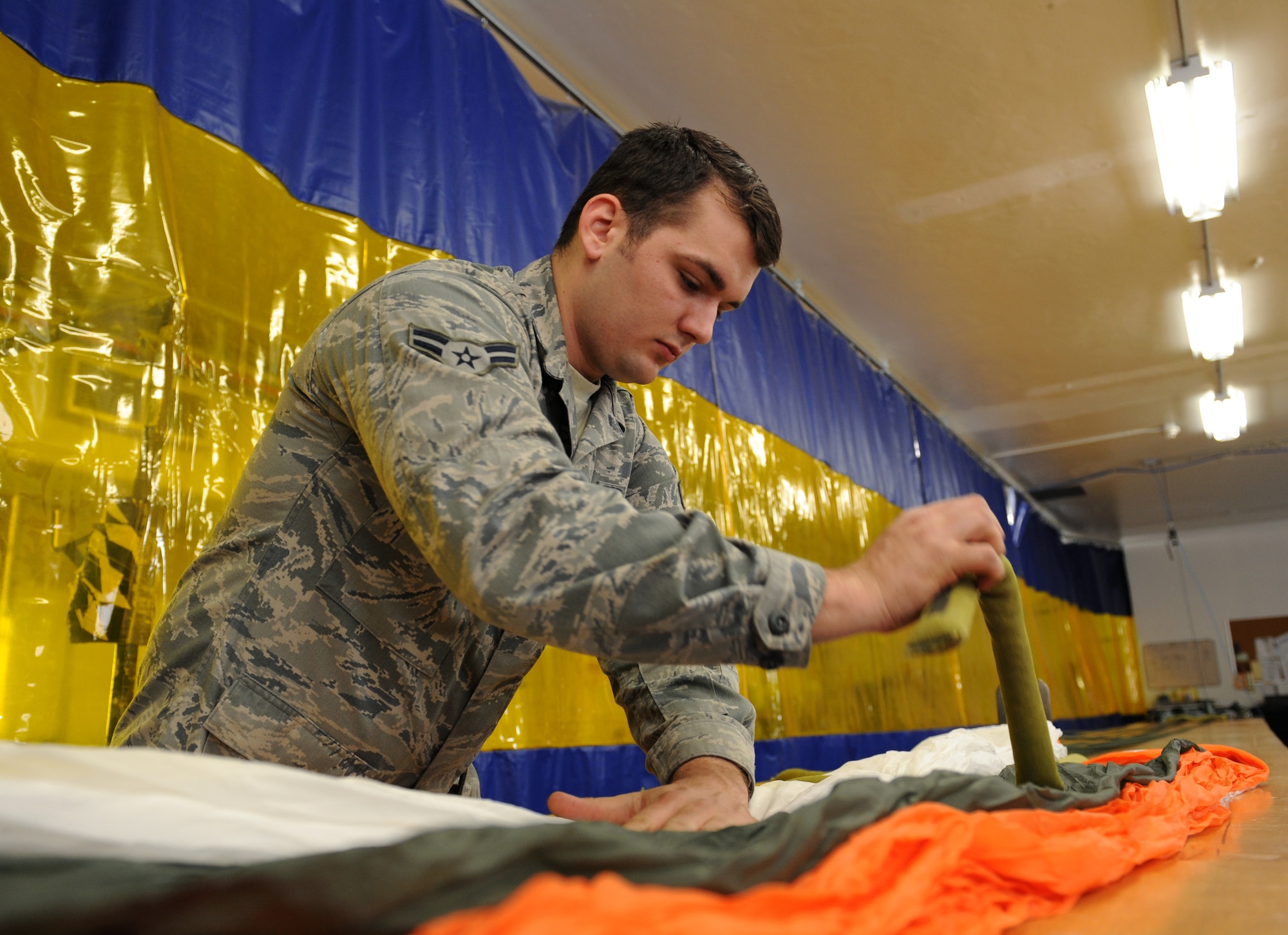 Airman 1st Class Richard James, 2nd Operations Support Squadron Aircrew Flight Equipment Parachute Shop, overlaps a parachute canopy onto itself on Barksdale Air Force Base, La., March 5. The AFE parachute shop is in charge of packing, inspecting and supplying B-52H Stratofortress aircrew with their parachutes. (U.S. Air Force photo/Airman 1st Class Benjamin Gonsier)
