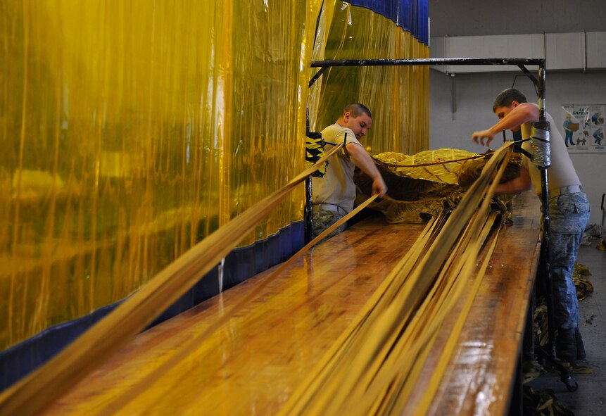 Senior Airman Kelly Adkins and Airman 1st Class Tyler Shepherd, 2nd Operations Support Squadron Aircrew Flight Equipment Parachute Shop, separates drag chute suspension lines on Barksdale Air Force Base, La., March 5. The drag chute lines are separated and then tied together to ensure they do not tangle during packing or when they are released for emergency use. (U.S. Air Force photo/Airman 1st Class Benjamin Gonsier)