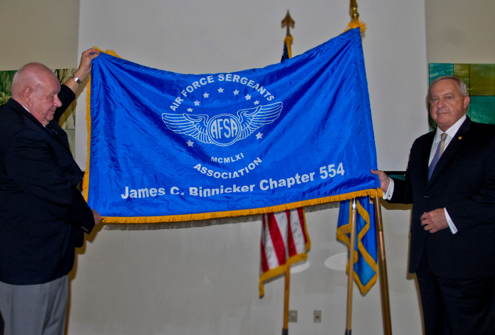 Retired Chief Master Sgt. of the Air Force James C. Binnicker (right), a member of the Air Force Sergeants’ Association, Chapter 554, and AFSA Division 2 president, Colin M. Gates, unfurl the new chapter flag showing the chapter’s renaming in Binnicker’s honor, at a ceremony Feb. 27 at the Crossroads at Eglin Air Force Base, Fla.  Binnicker was the ninth chief master sergeant of the Air Force.  (U.S. Air Force photo/Kevin Gaddie)