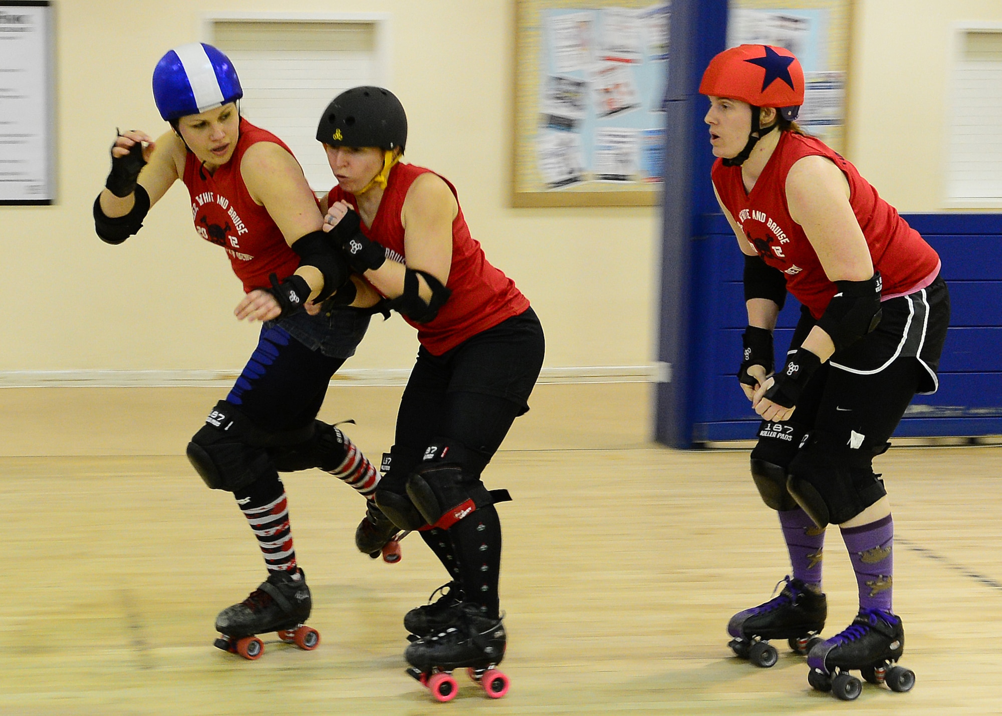 ROYAL AIR FORCE LAKENHEATH, England – Red, White and Bruises Rollers derby players Tarnna Hernandez (center), blocks Kay Daniels (left), from getting in front of Debby Rodriguez, the jammer, Feb. 21, 2013. RWBR is a private derby league at RAF Lakenheath and is open to women 18 years or older with a base access. (U.S. Air Force photo by Staff Sgt. Stephanie Mancha)