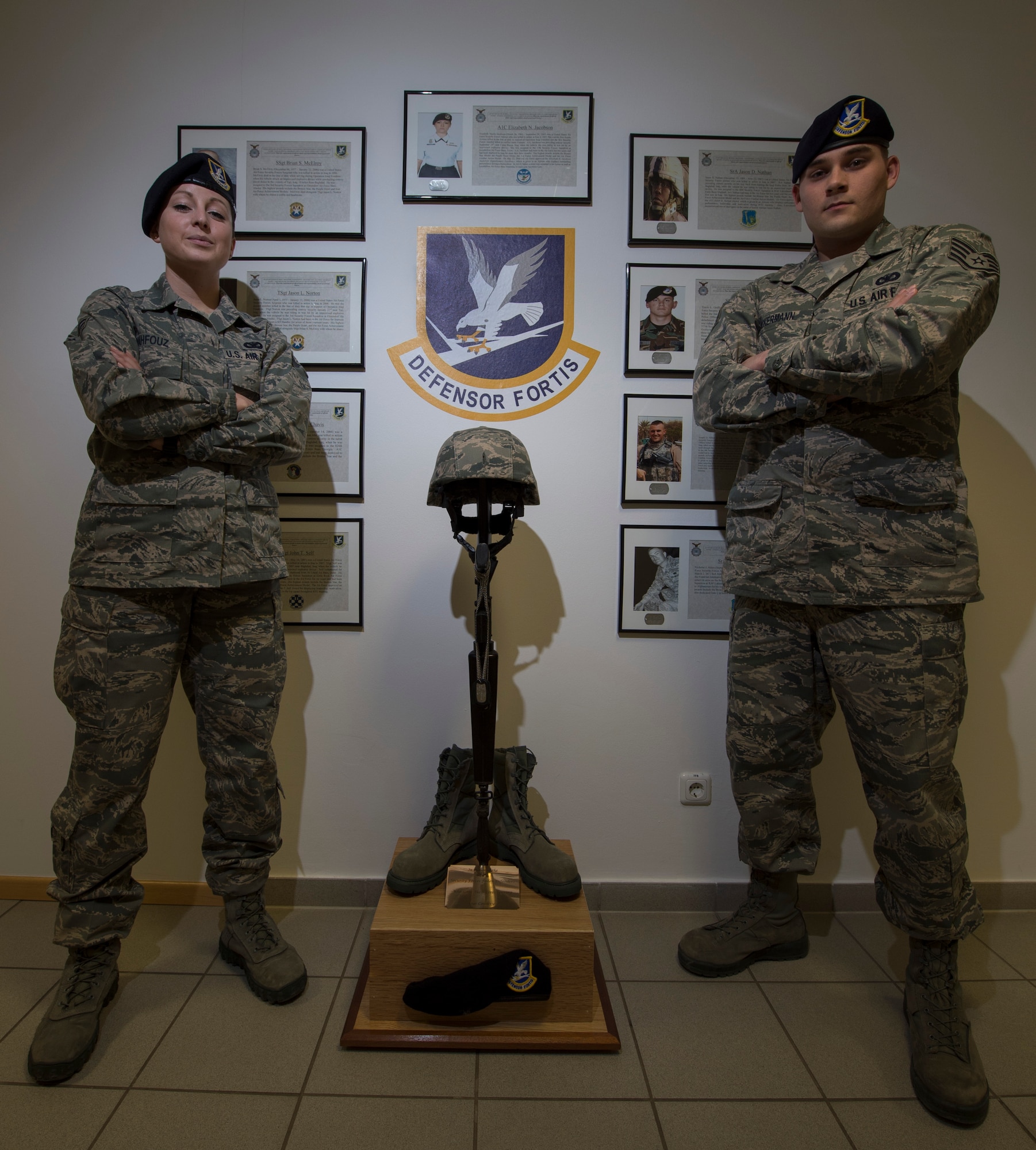 SPANDGDAHLEM AIR BASE, Germany -- U.S. Air Force Senior Airman Lindsey Mahfouz, left, 52nd Security Forces Squadron member from Lincoln, Calif., and Staff Sgt. Robert Ackerman, 52nd SFS member from Long Island, N.Y., stand in front of the 52nd SFS Fallen Defenders Memorial after putting it together March 1, 2013. Mahfouz worked with Ackerman to find information about the nine fallen security forces members featured in the memorial. (U.S. Air Force photo by Senior Airman Natasha Stannard/Released)