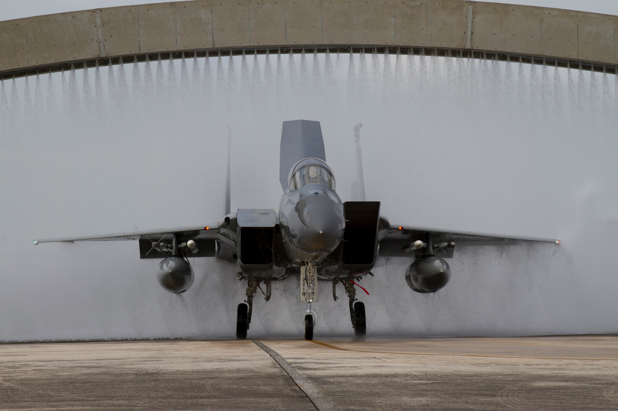 A 44th Fighter Squadron F-15 Eagle fighter aircraft goes through a "bat bath" on Kadena Air Base, Japan. The "Vampire Bats" run their aircraft through the bath after the last sortie each day to wash off salt water. (Courtesy photo by Jake Melampy)
