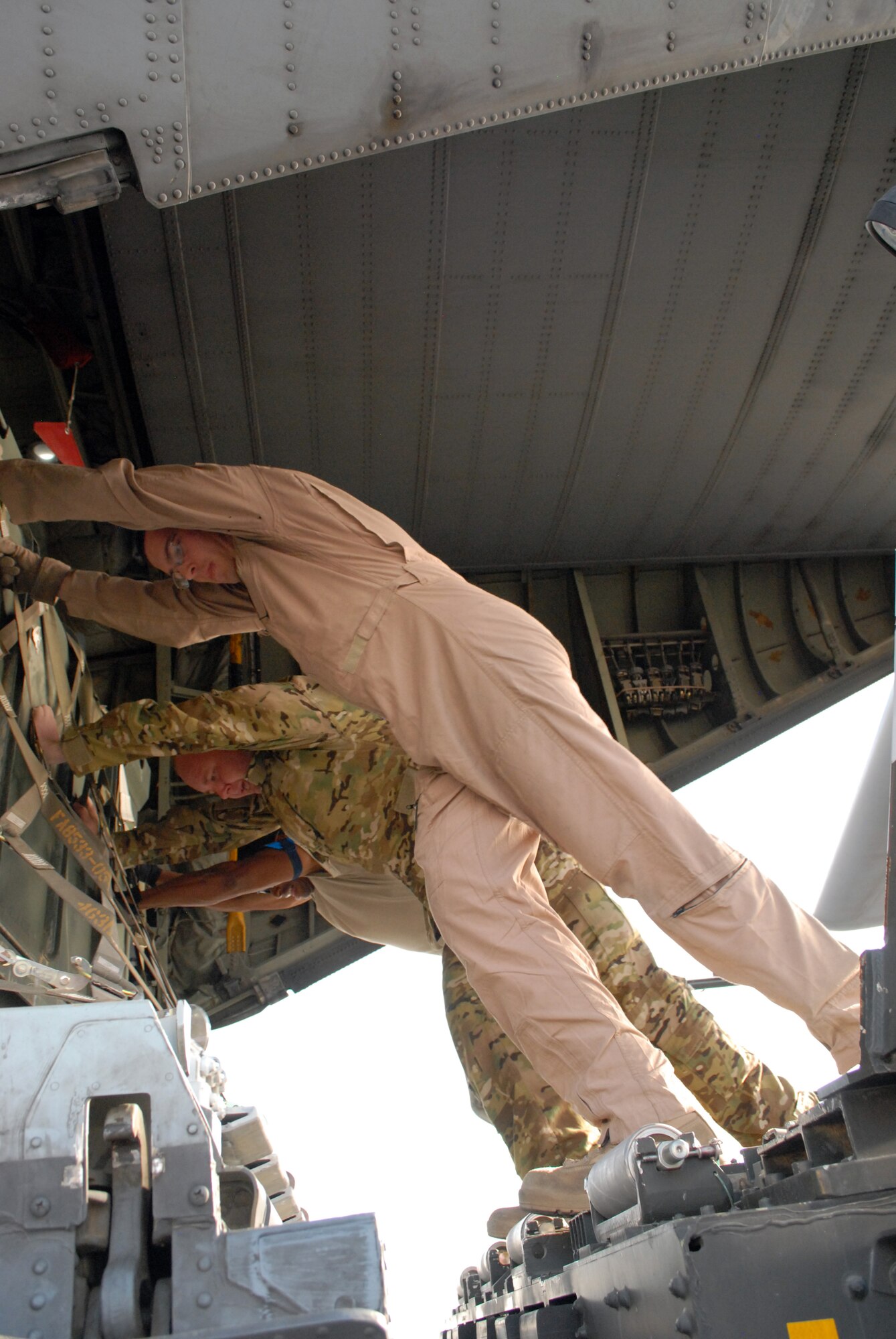SOUTHWEST ASIA -- Senior Airman Nathan Basham and Staff Sgt. Ian Hughes, 746th Expeditionary Airlift Squadron, and  Tech. Sgt. Kvaven Barker, 8th Expeditionary Air Mobility Squadron, push a pallet into place from  K-loader onto a C-130, Mar. 4. Members of the 746th Expeditionary Airlift and Expeditionary Aircraft Maintenance Squadrons, comprised of Reservists from the 908th Airlift Wing, Maxwell AFB, Ala., and 440th Airlift Wing, Pope Field, N.C., prepare to transport cargo downrange in the U.S. Central Command area of responsibility. (U.S. Air Force photo/Master Sgt. Christian Michael)