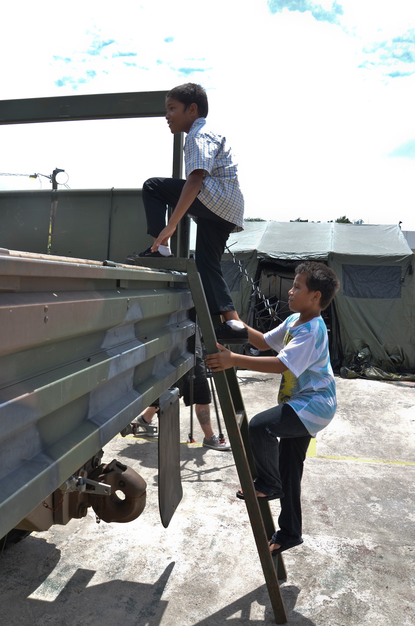 Jeffer Lorenzo and Zaine Baker, Umatac residents, take a tour of a 644th Combat Communications Squadron vehicle during Discovery Day in Umatac, Guam, March 2, 2013. The Sister Village program allows a squadron from Andersen to partner with a local village and develop relationships with local community members. (U.S. Air Force photo by Staff Sgt. Veronica McMahon/Released)